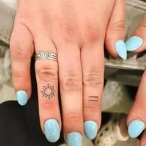 Hand with three tattoos on fingers and painted light blue nails.