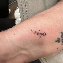 A tattoo of a constellation and star on a person's forearm.