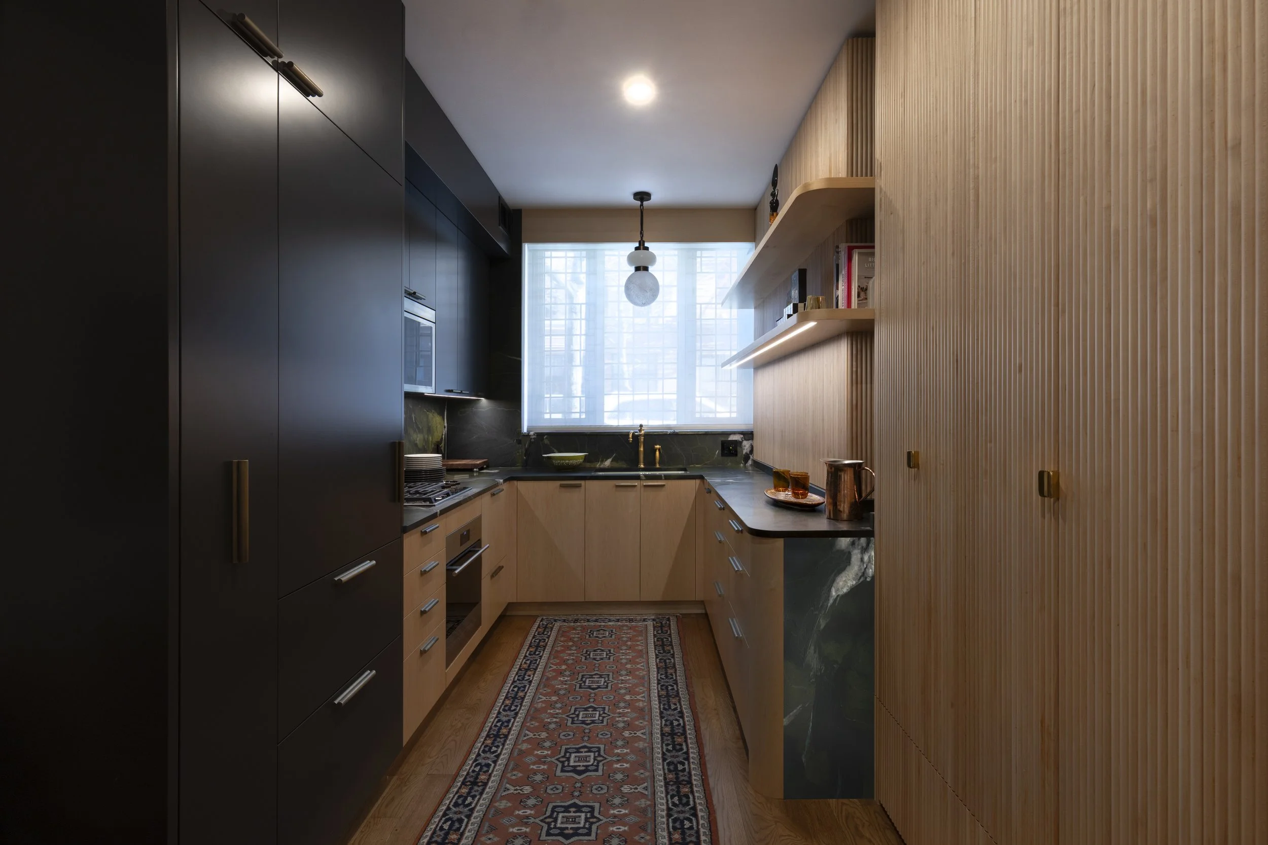 Kitchen: Brooklyn apartment kitchen with fluted wood cabinetry, Avocatus stone, and integrated appliances.