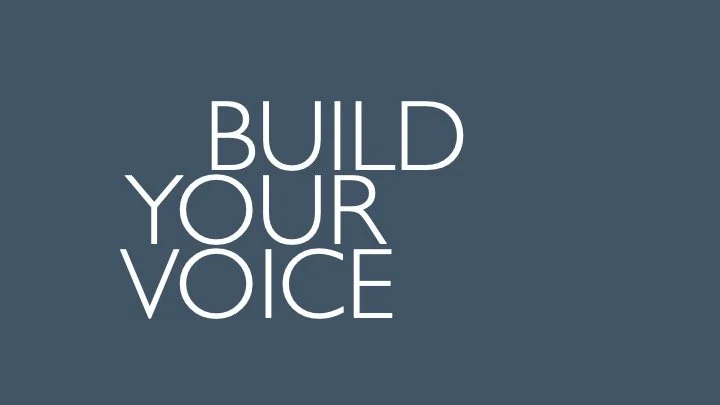 Text on a dark gray background says, 'BUILD YOUR VOICE' in white, uppercase letters.