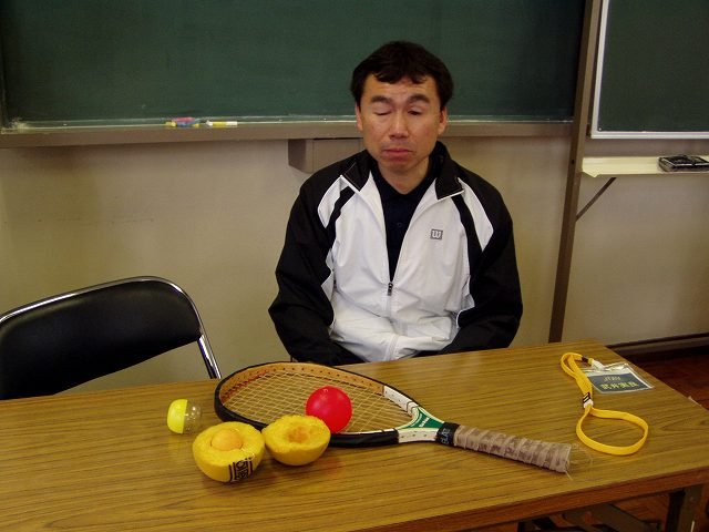 Takei sitting at a table with a blind tennis racket and a sound ball. Photo courtesy of Ayako Matsui