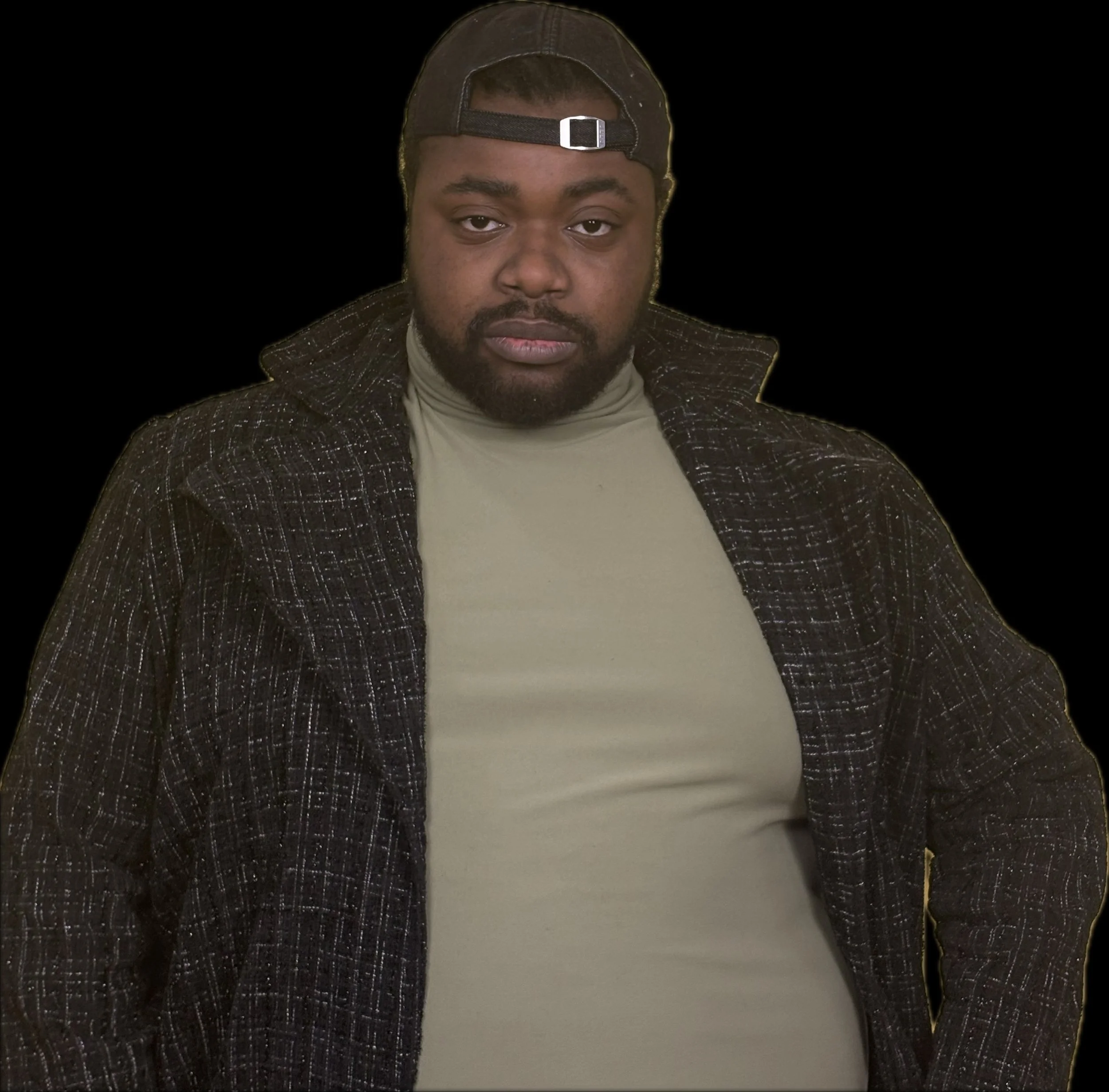 A young man in a beige turtleneck, dark jacket, and cap looks directly at the camera against a black background.