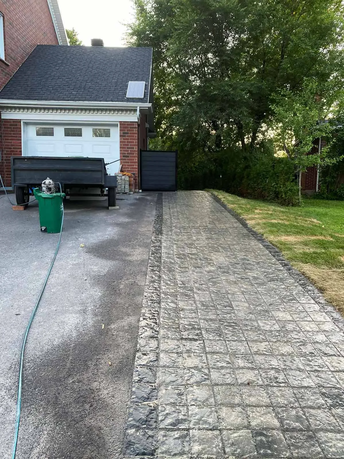 Allée pavée près d’un garage avec clôture noire, aménagement extérieur et terrassement à Québec.