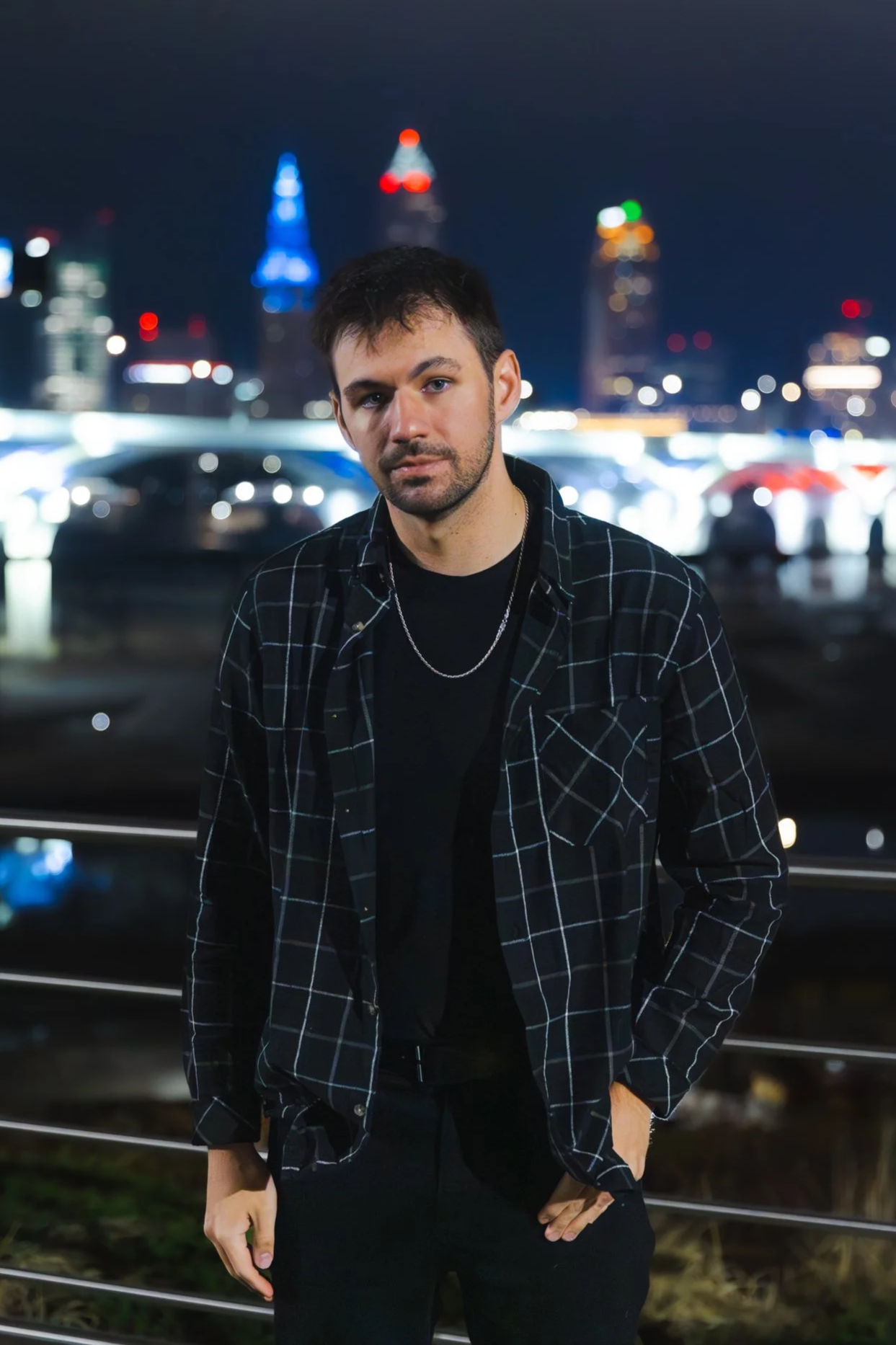 Alby is standing at night with the Cleveland skyline and illuminated buildings in the background.