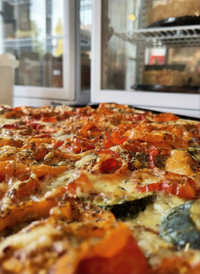Eine frisch gebackene Pizza mit Tomaten, Paprika, Käse und anderen Belägen in einem Pizzaofen.