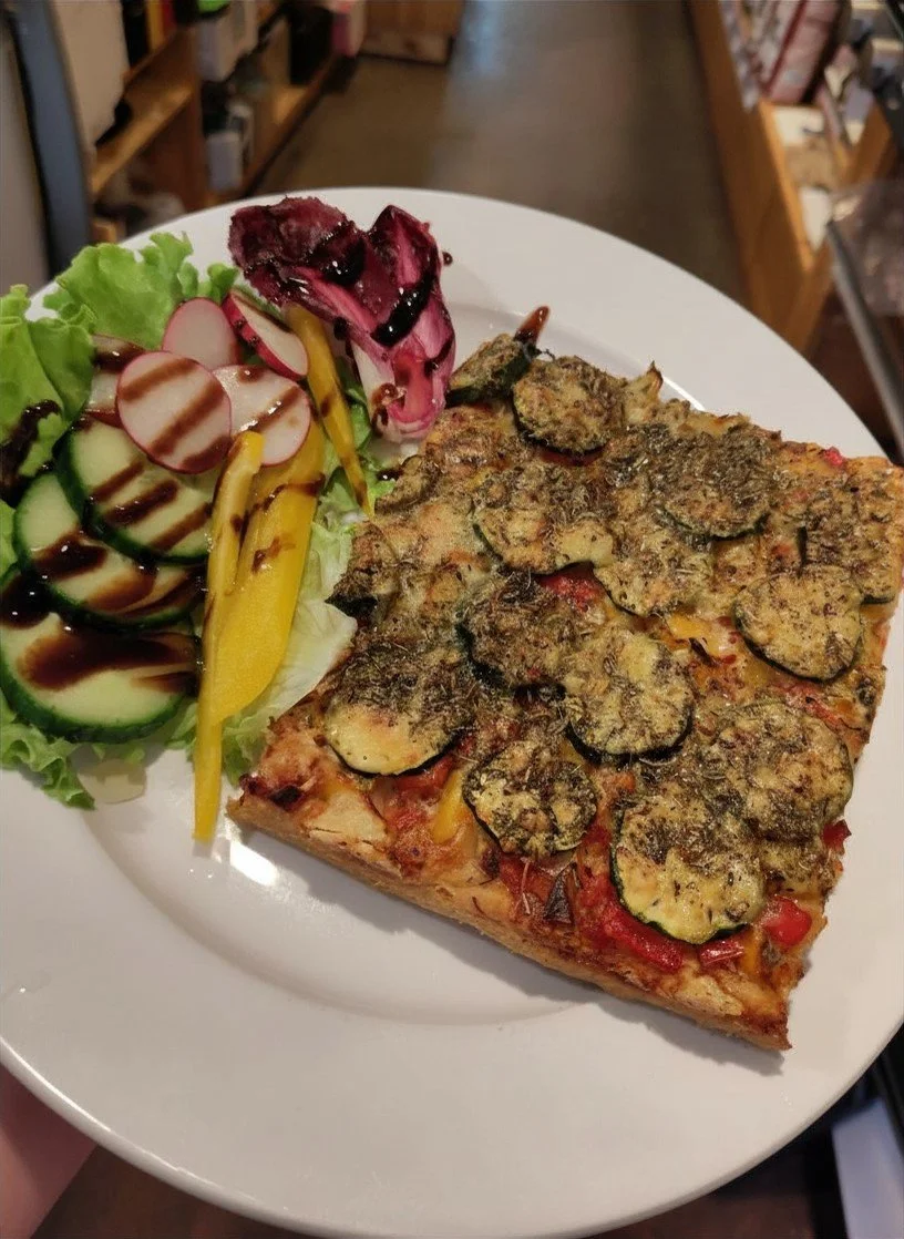 Ein Teller mit Pizza, Salat mit Gurken, Radieschen und Paprika, und balsamico-Glasur
