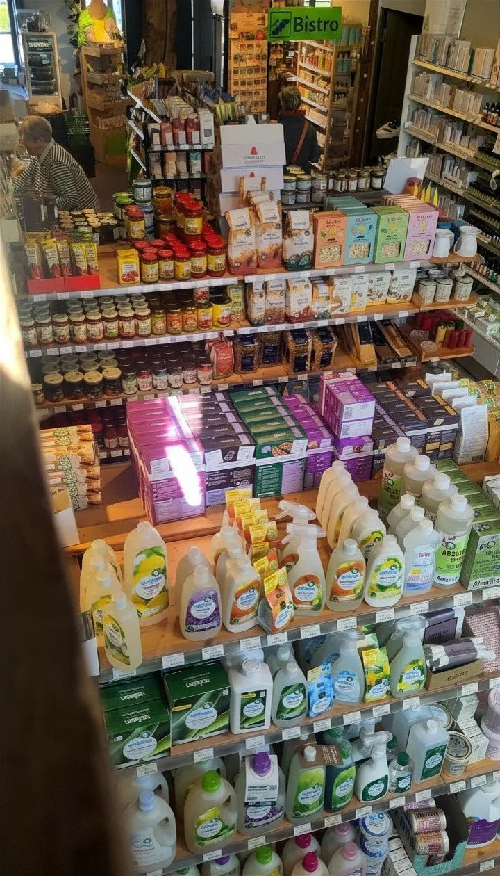 Regal mit Bio-Haushalts- und Reinigungsprodukten, Marmeladen, Tees und Trockenlebensmitteln in einem Biomarkt.