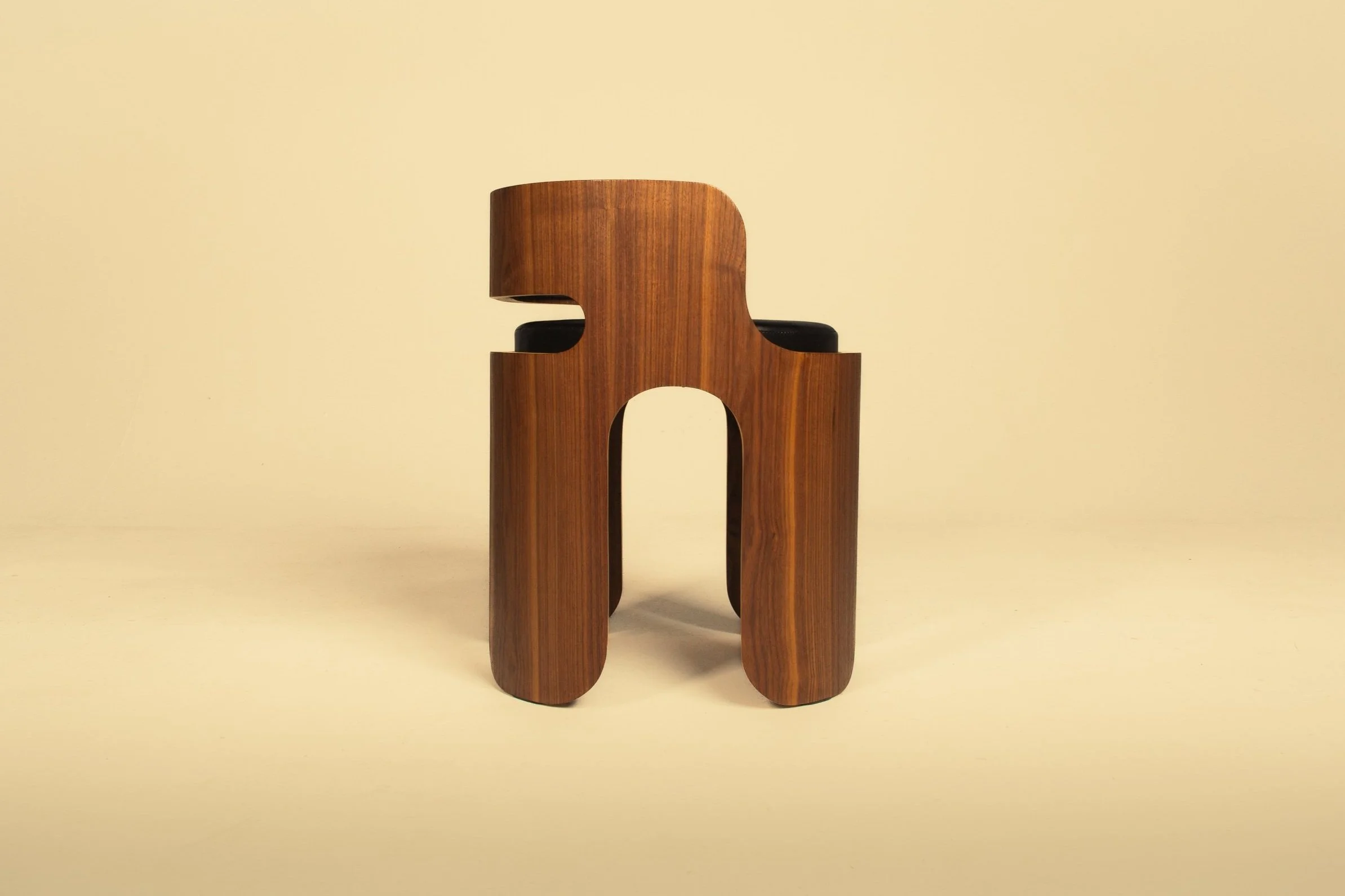 A modern wooden chair with a curved backrest and black cushioned seat, designed with a minimalist aesthetic.
