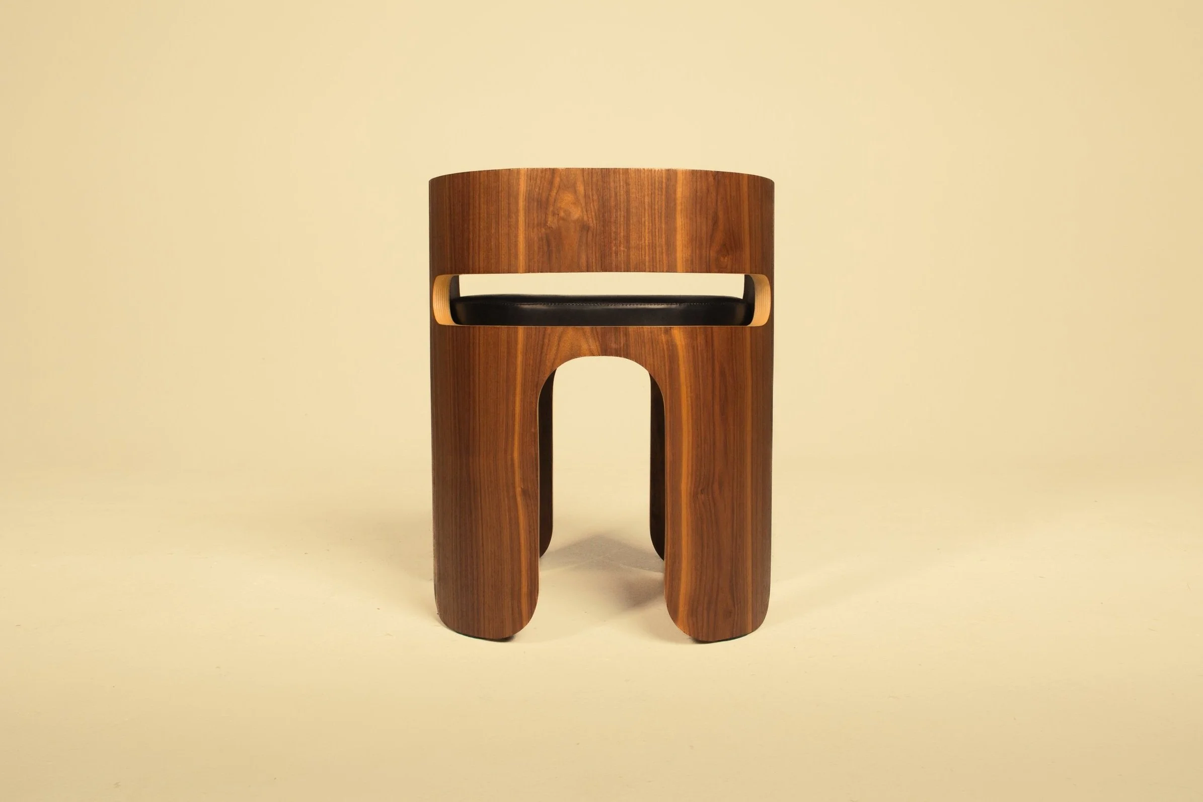 A modern wooden stool with a circular seat and rounded legs on a light background.
