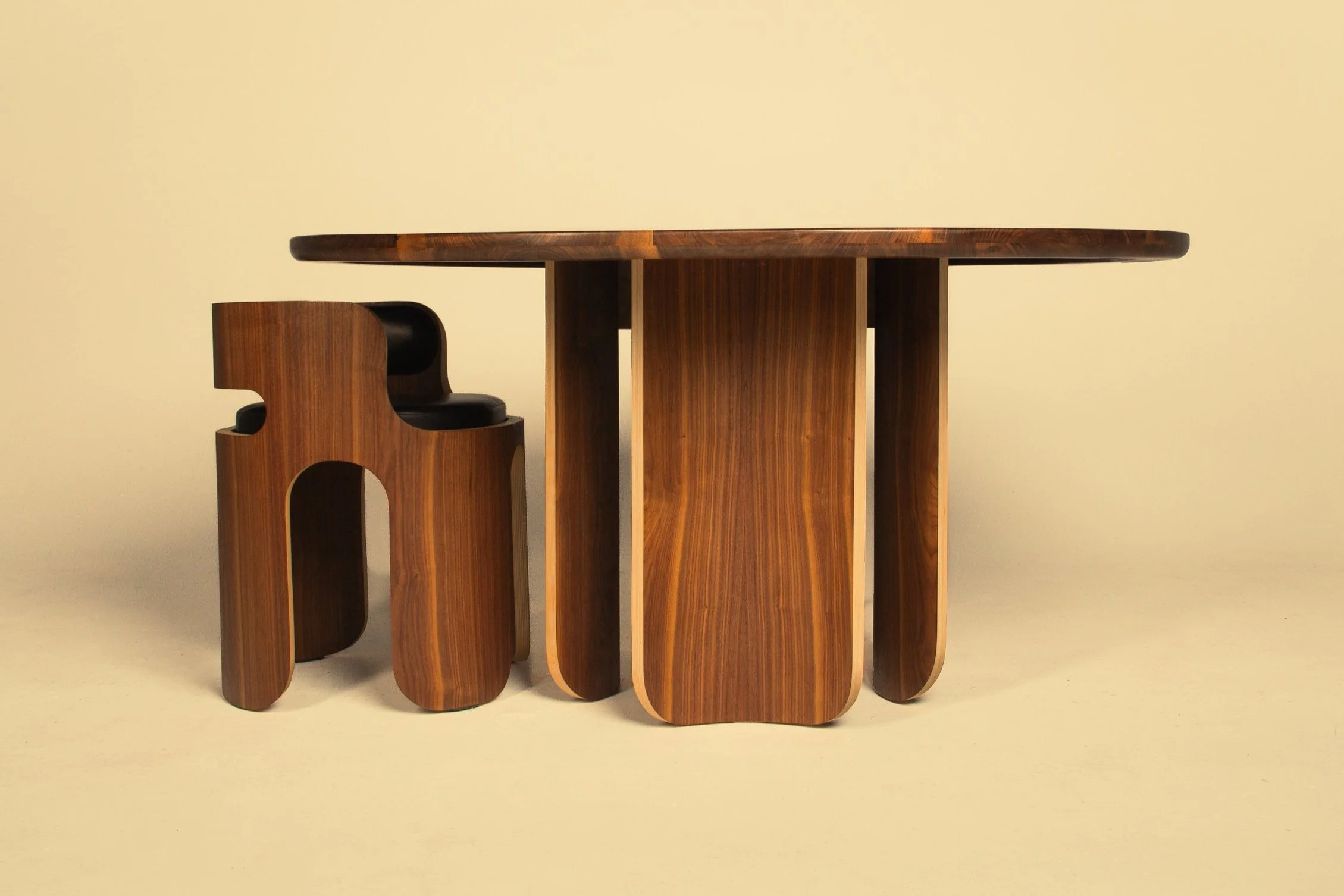A wooden dining table with a matching chair, both featuring sleek, curved designs made from dark and light wood.
