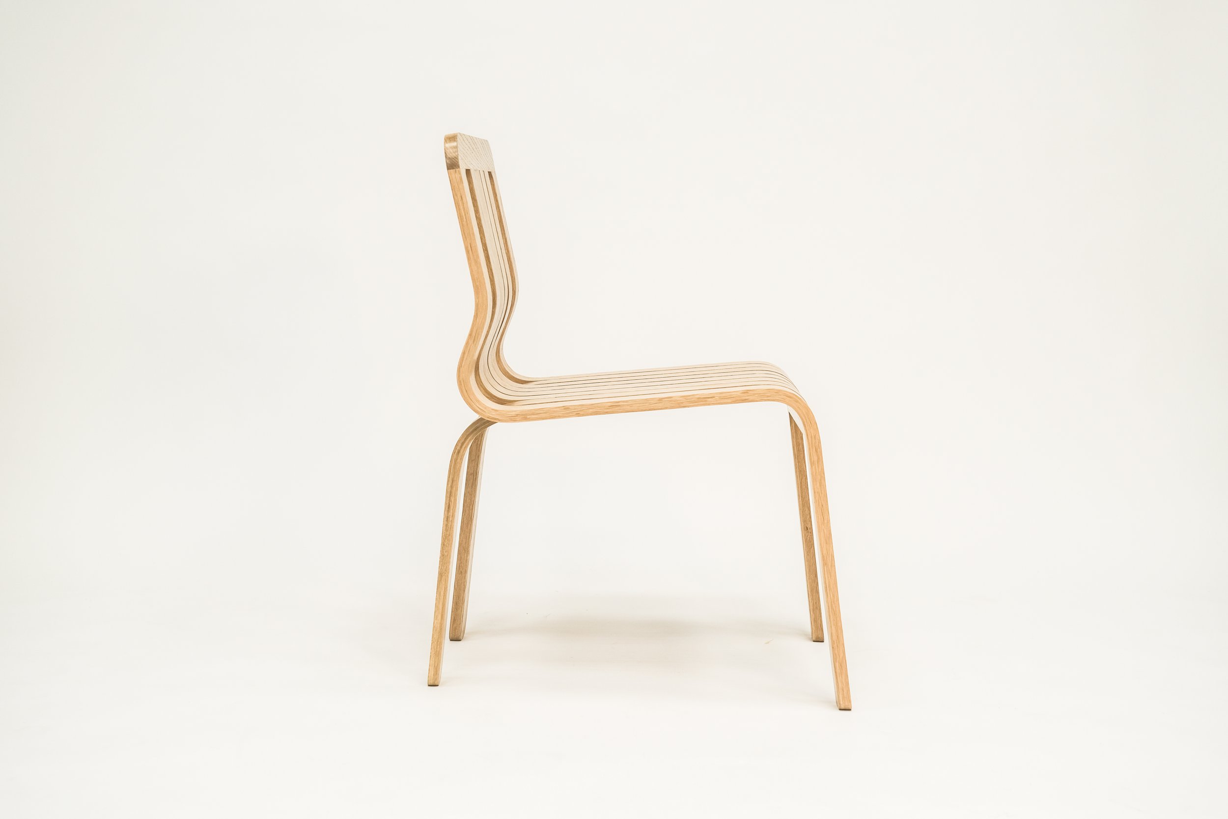 A minimalist wooden chair with a curved backrest and four straight legs, set against a plain white background.