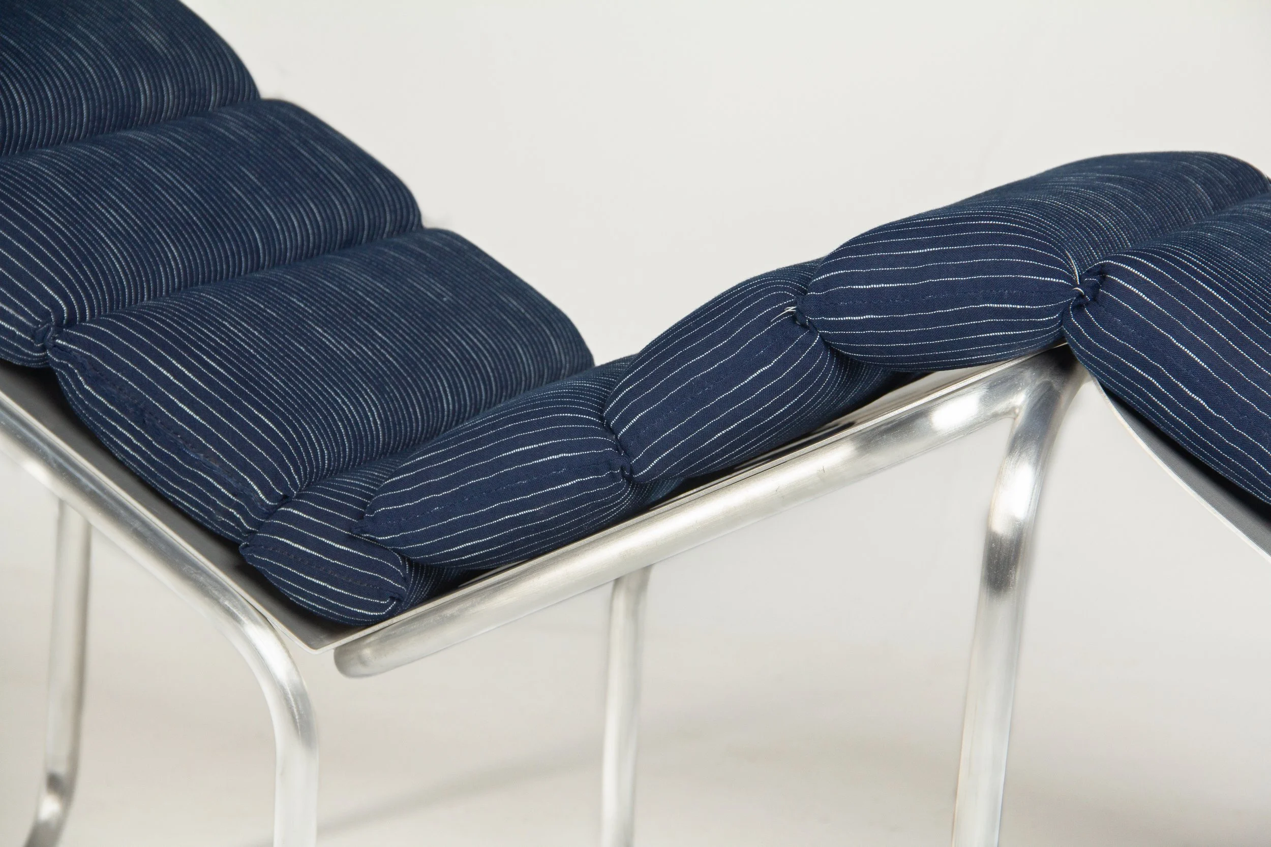 A modern lounge chair with a metal frame and blue striped cushions.