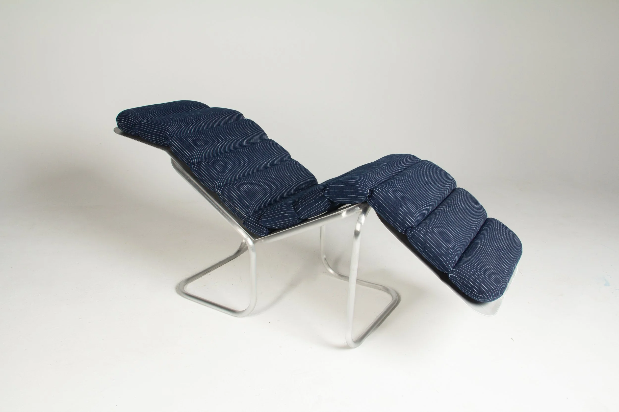A modern lounge chair with a metal frame and dark blue padded cushions.