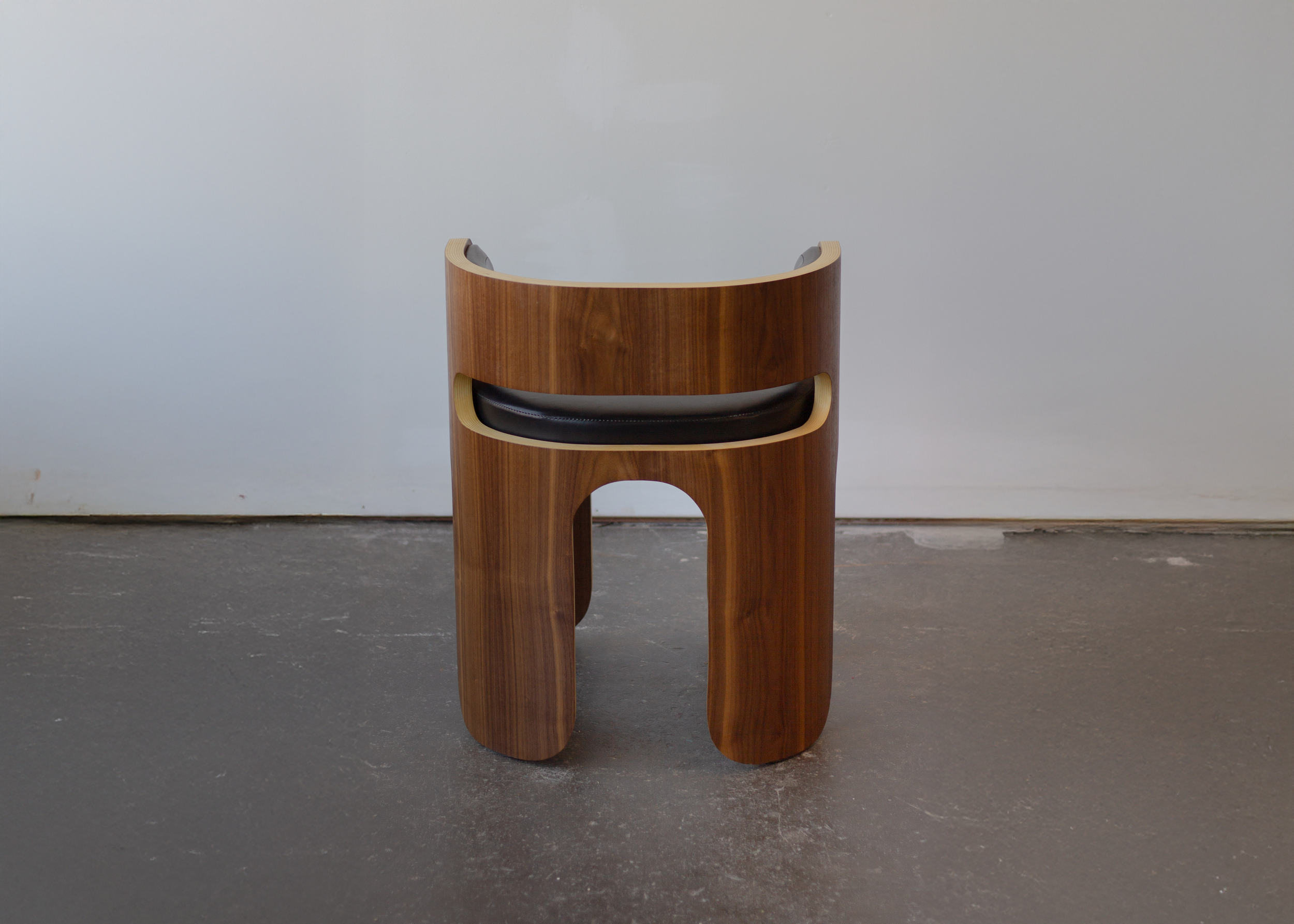 A modern wooden stool with a circular seat and rounded legs on a light background.