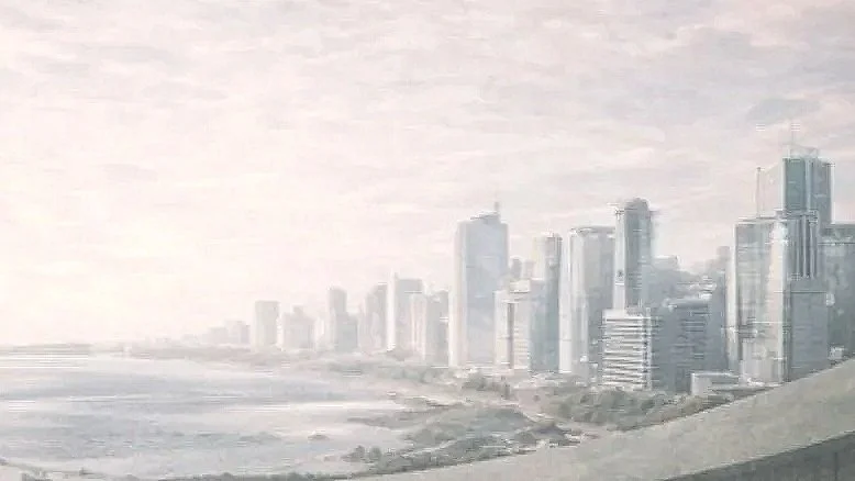 Skyline of a modern city with tall skyscrapers near a body of water in a hazy atmosphere.