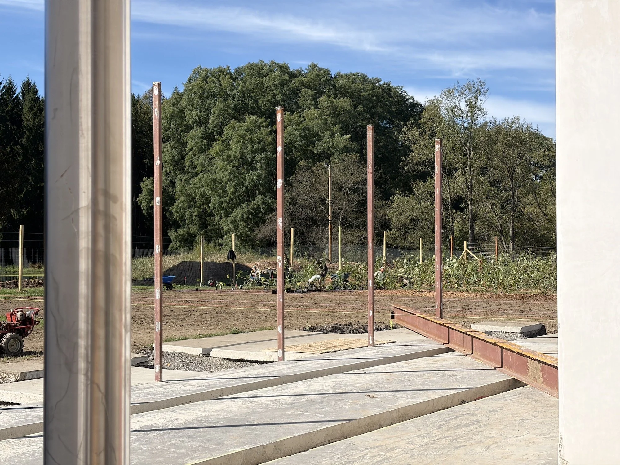 View through a wall opening toward exposed steel columns and concrete slabs.