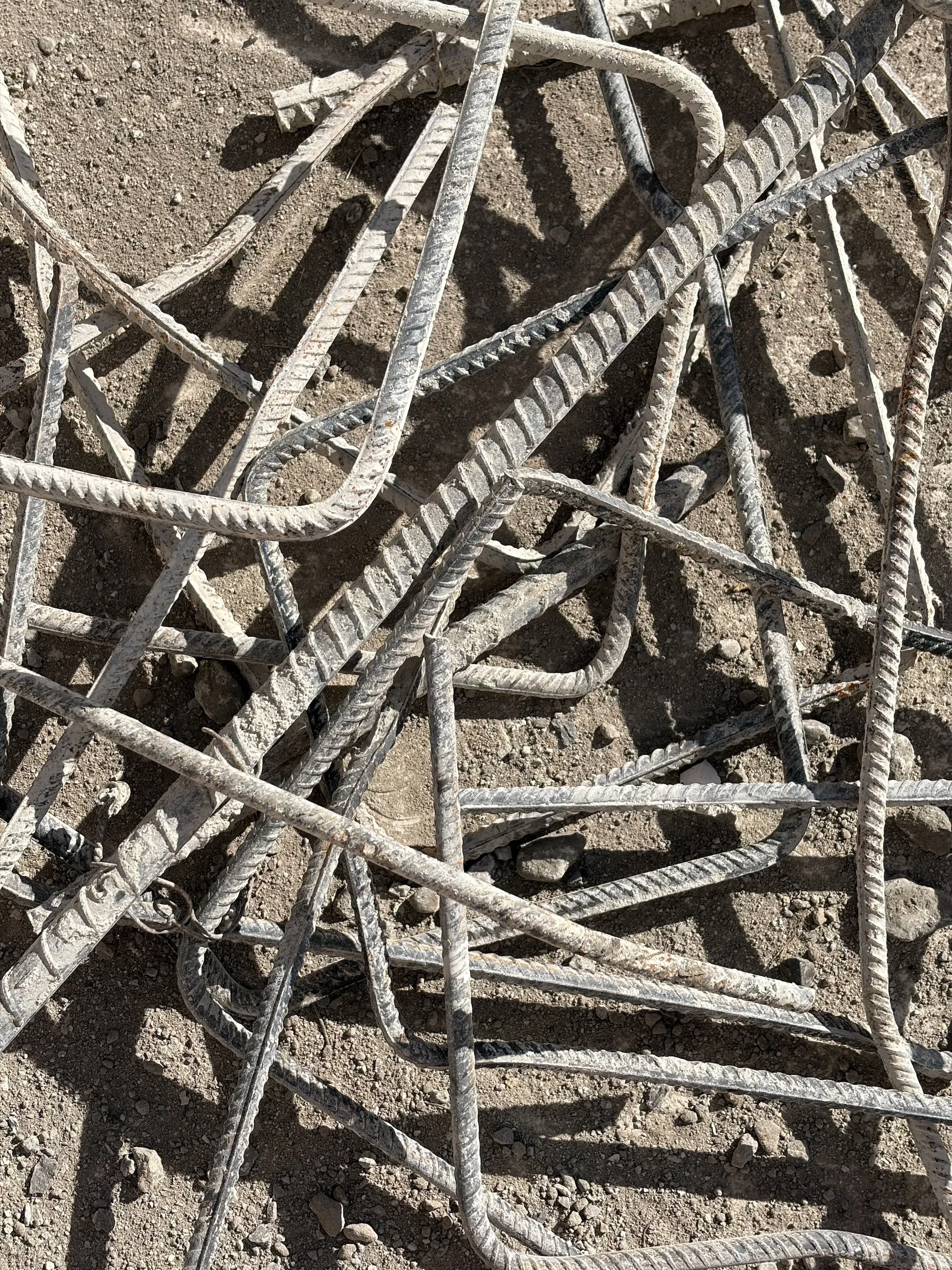Bent steel reinforcing bars scattered across soil and concrete debris.