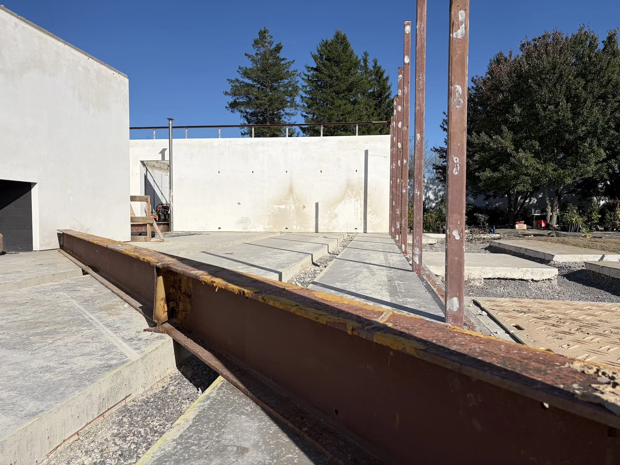 Rusted steel beam and upright columns beside retained concrete slabs.