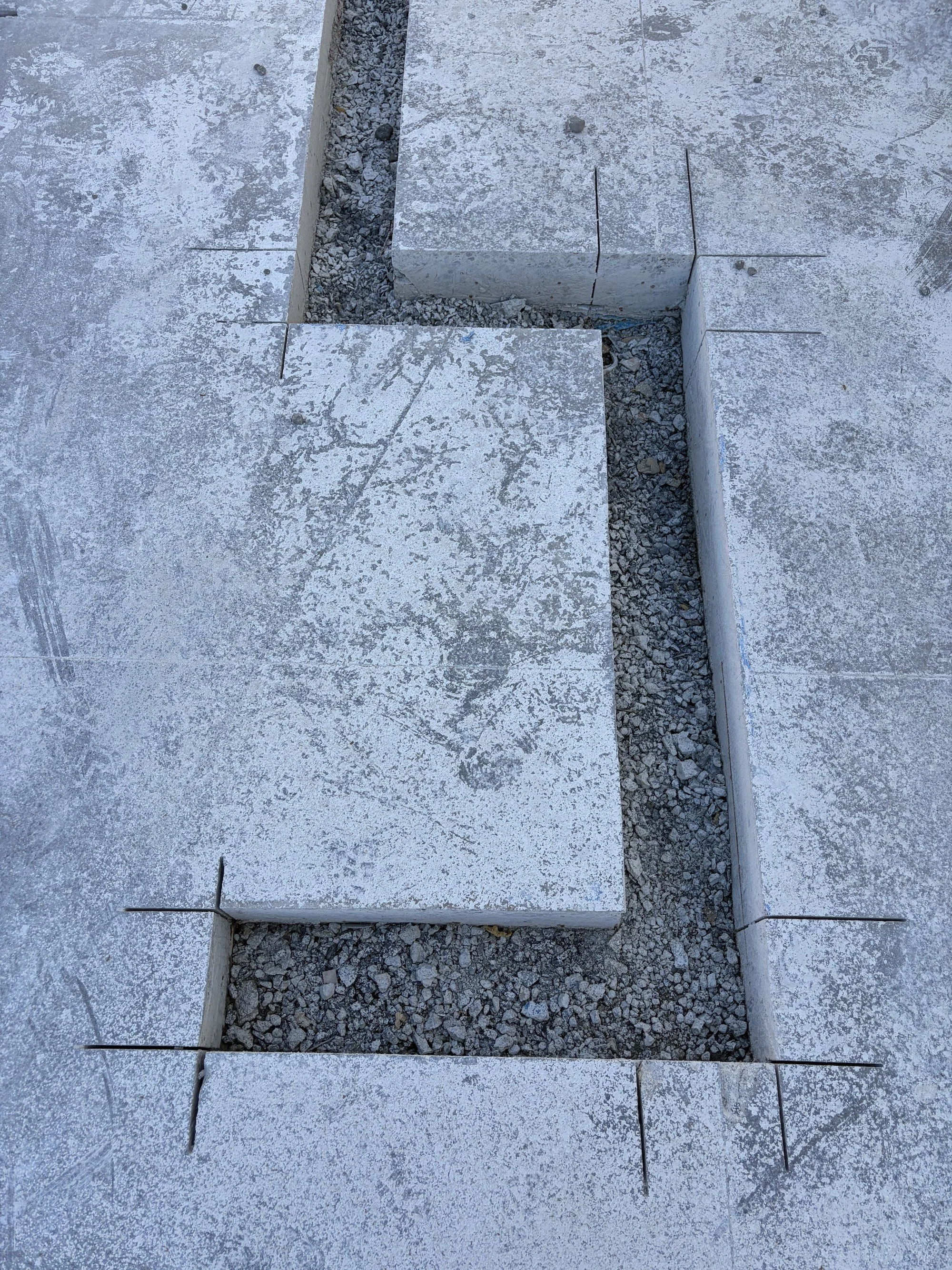 Close-up of cut concrete slabs separated by gravel-filled channels.