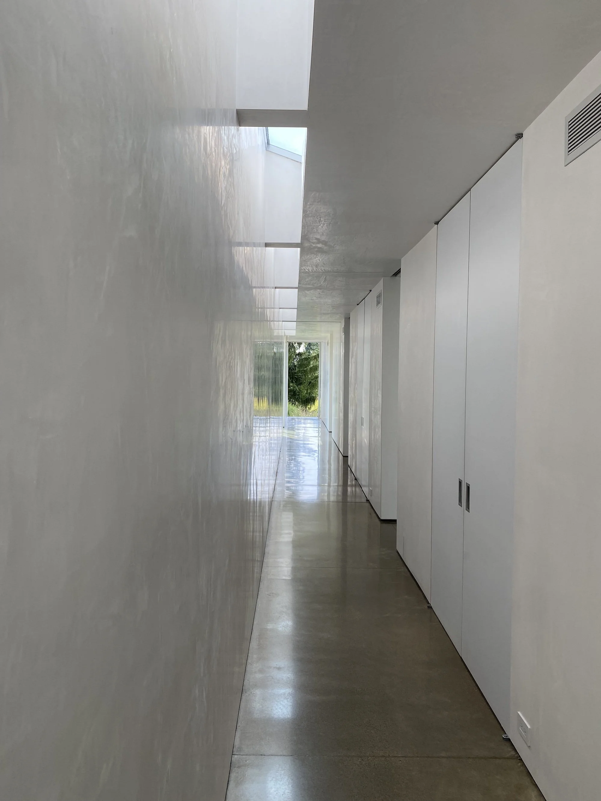 Long white hallway with skylights and a view toward the garden.