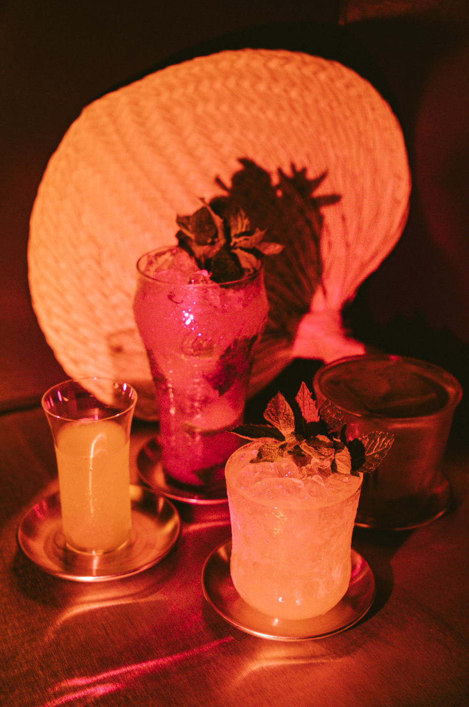 a warm yellow red photo of four different cocktails