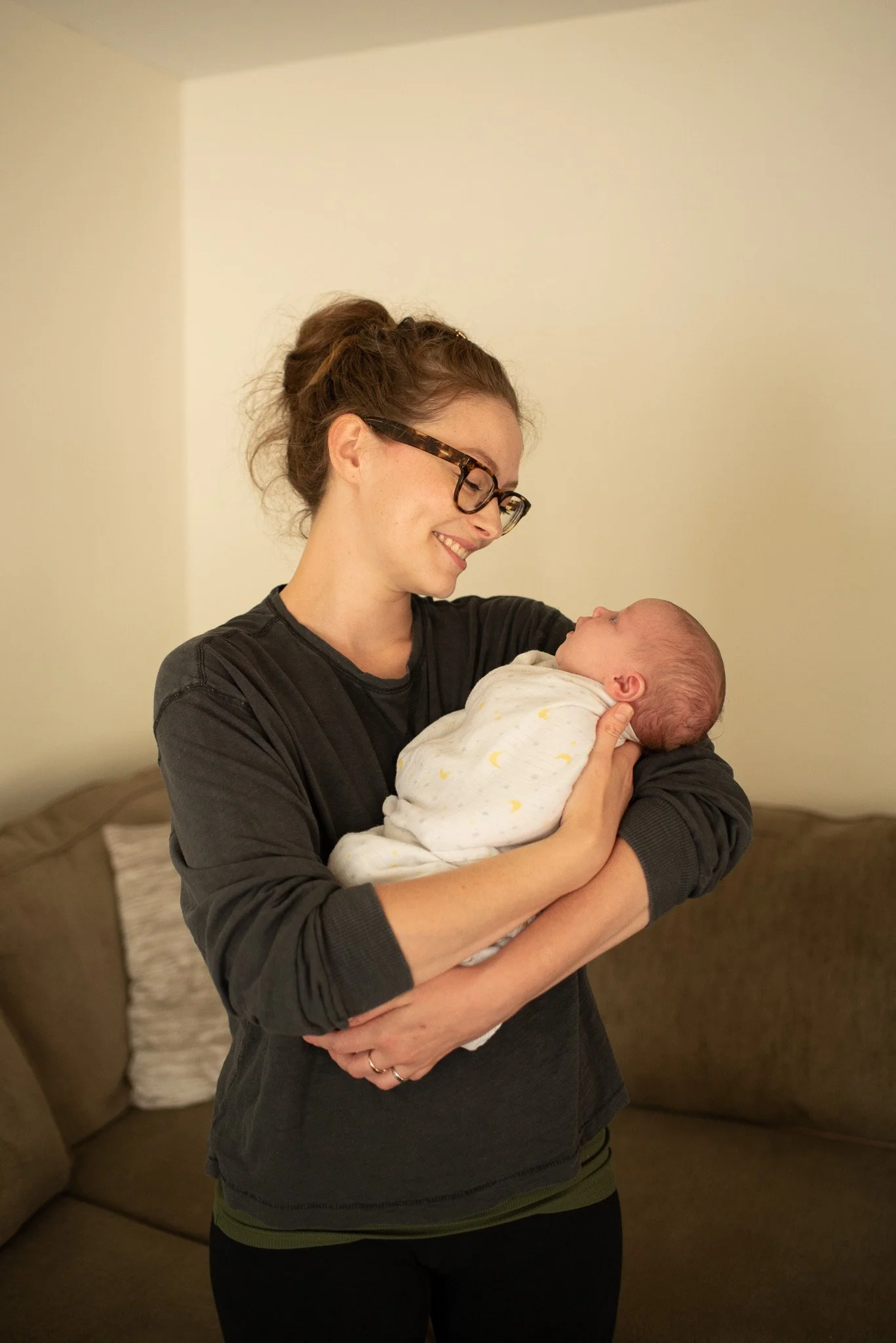 Birth doula in Kankakee County holding a newborn baby and smiling during a postpartum visit