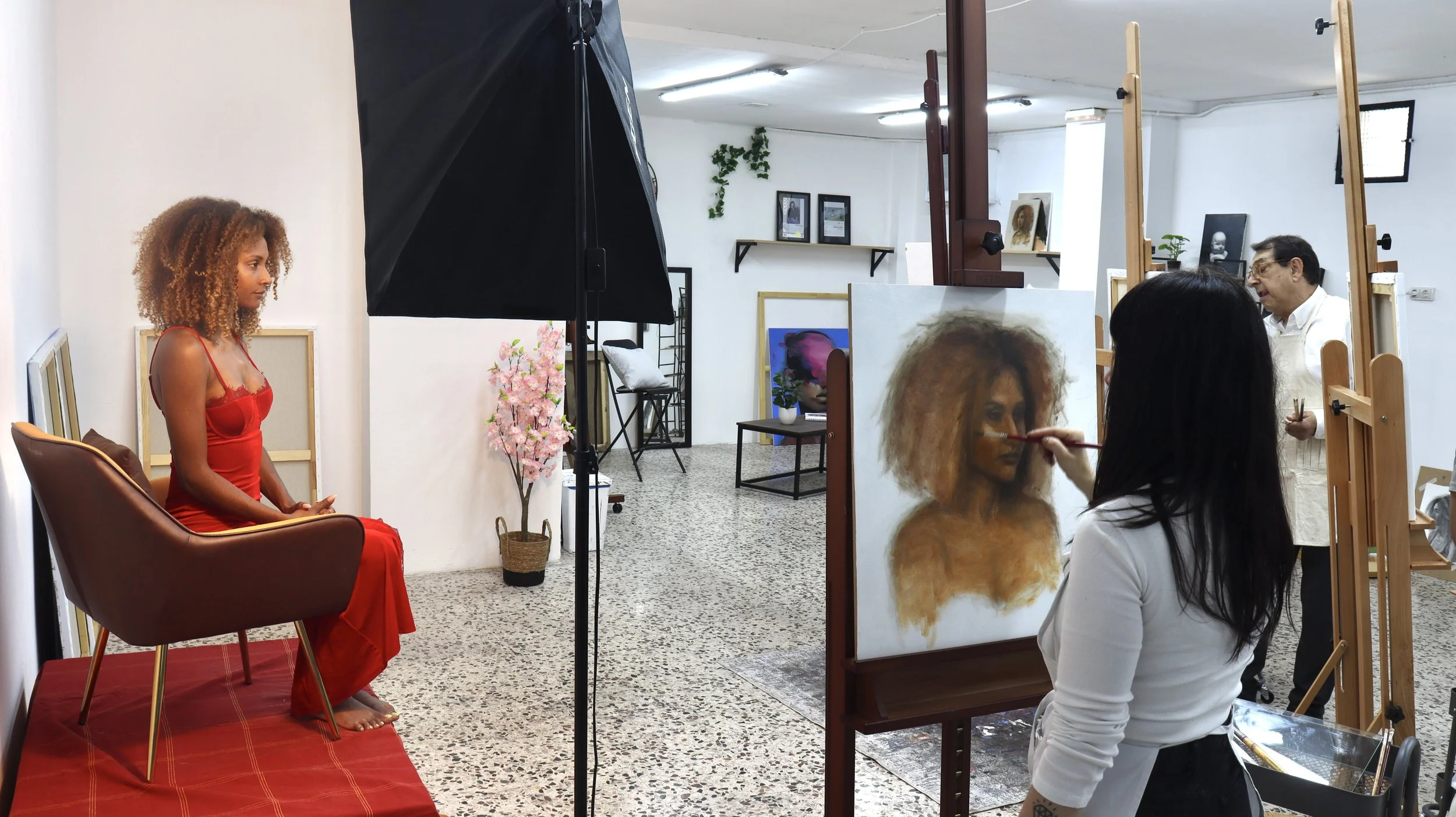 Un grupo de alumnos en un curso de pintura, con modelo del natural y artistas trabajando en retratos y obras de arte en el Atelier Pina.