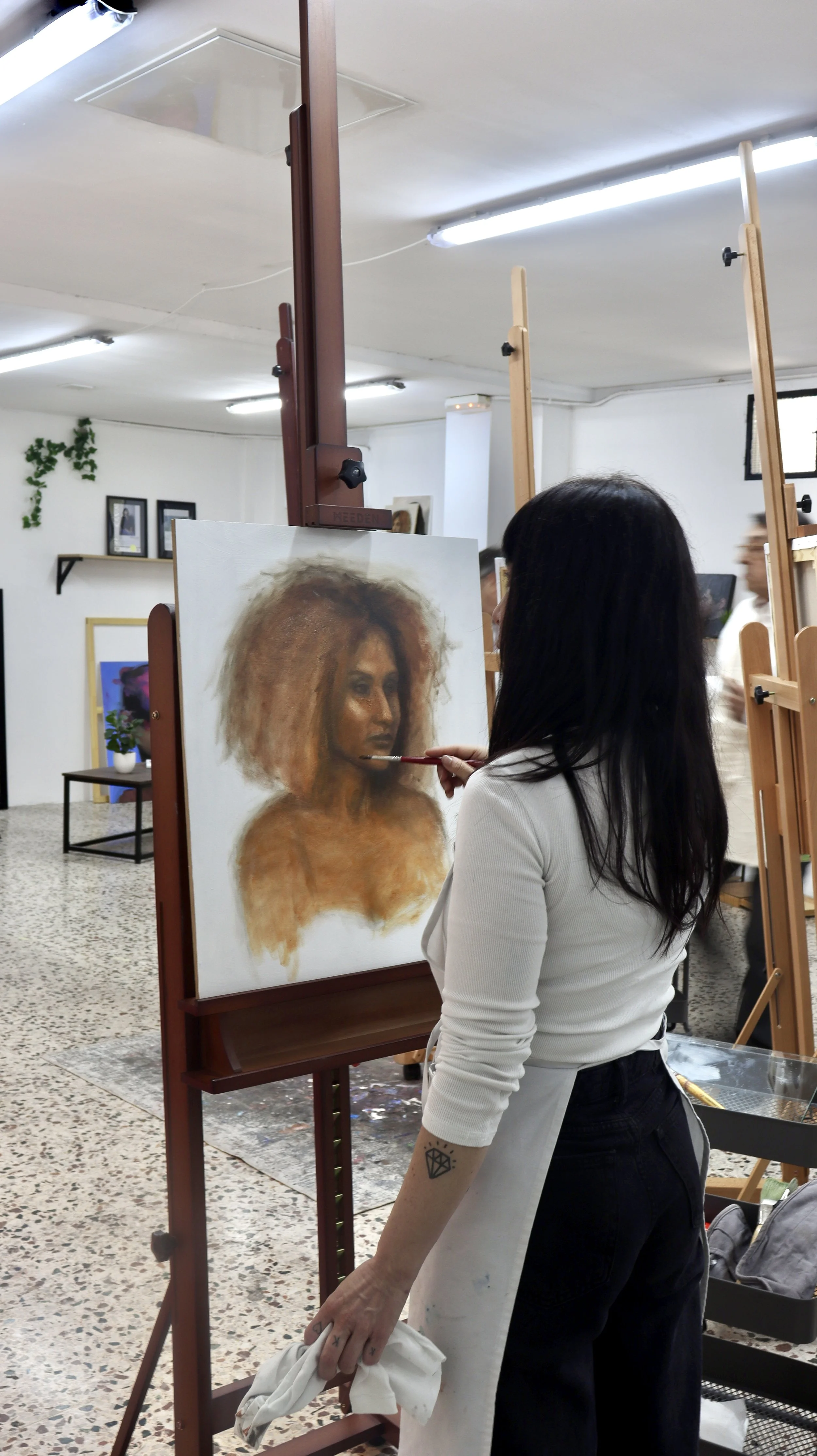 Una alumna pintando un retrato al oleo realista en Atelier Pina.