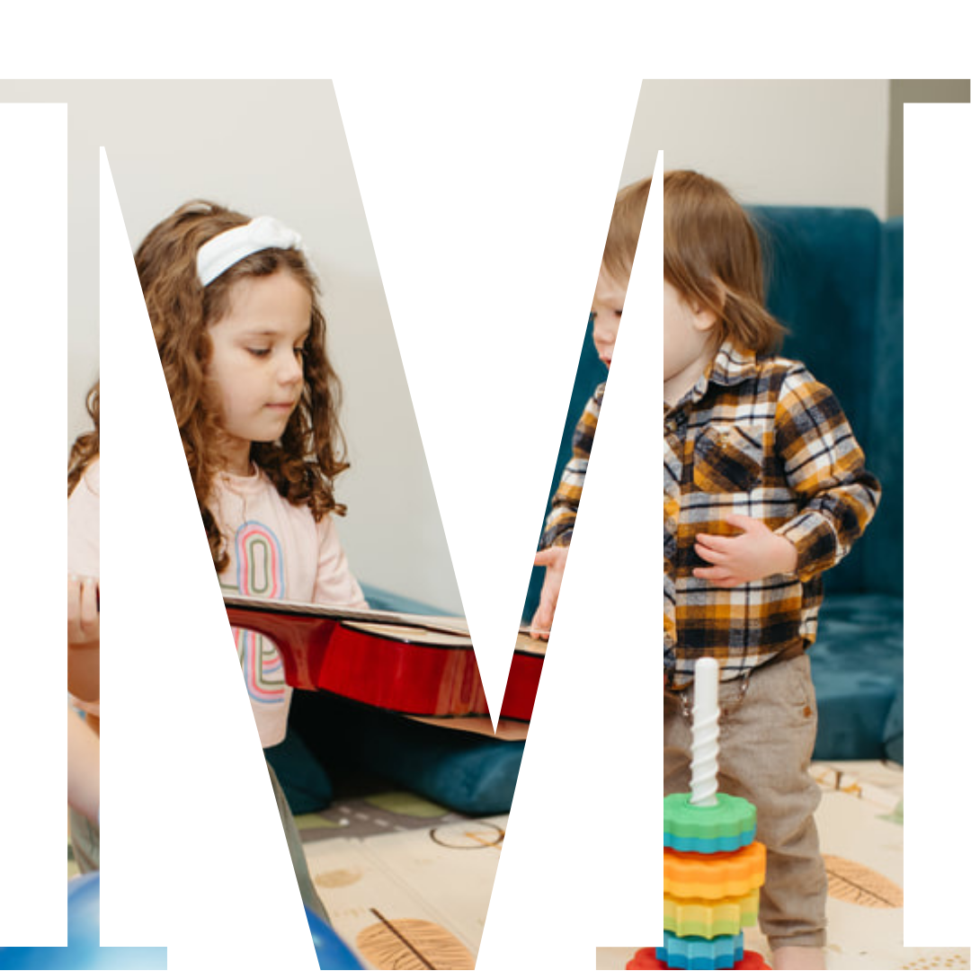 A young girl with curly hair wearing a white headband and pink shirt, holding a red guitar, and a young boy with straight hair in a plaid shirt playing with a colorful stacking toy, indoors with a blue couch and beige walls.