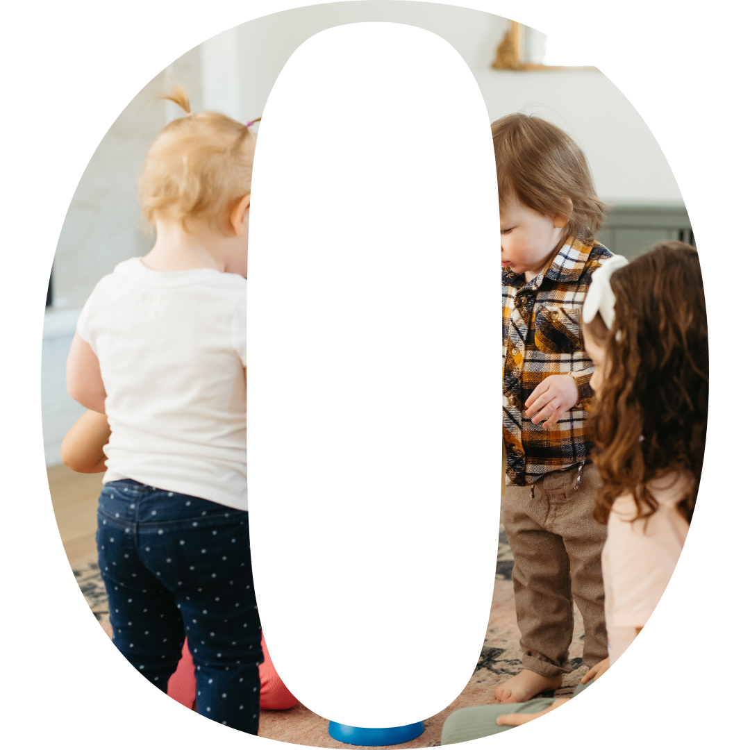 Three young children in a living room standing around a toy engaged in a group activity.