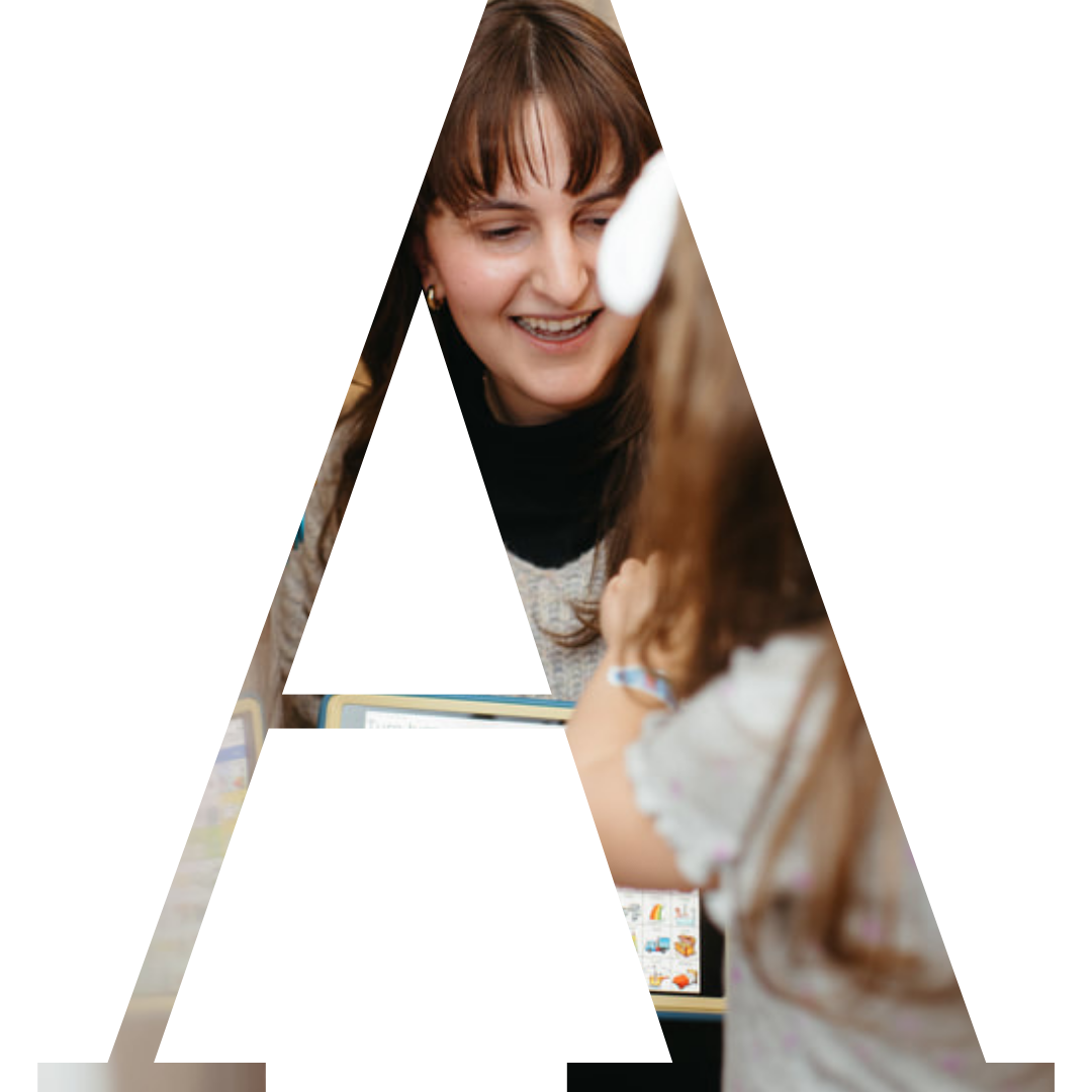 A woman smiling at a young girl with long hair, as they look at a computer screen.