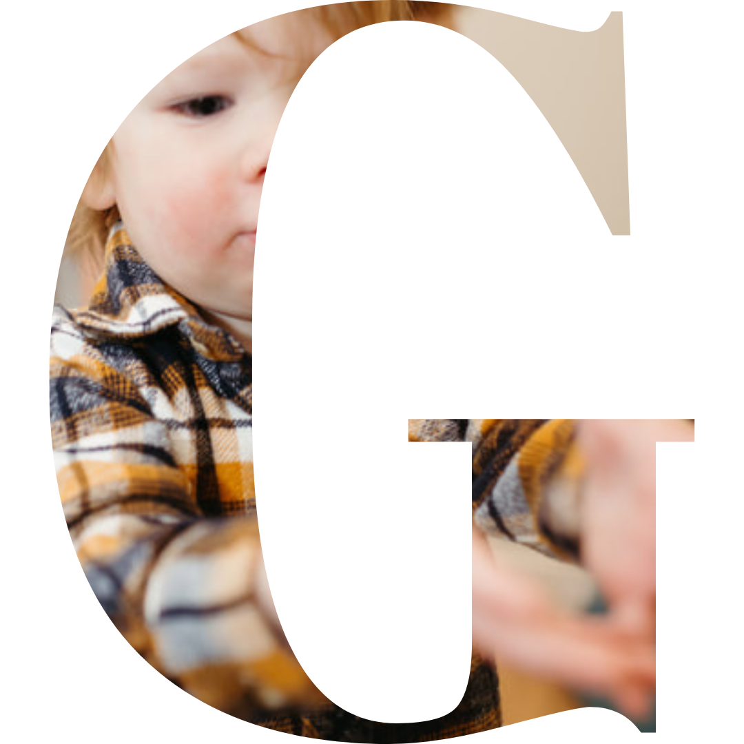 A young child with blonde hair wearing a plaid shirt reaches out their hand.