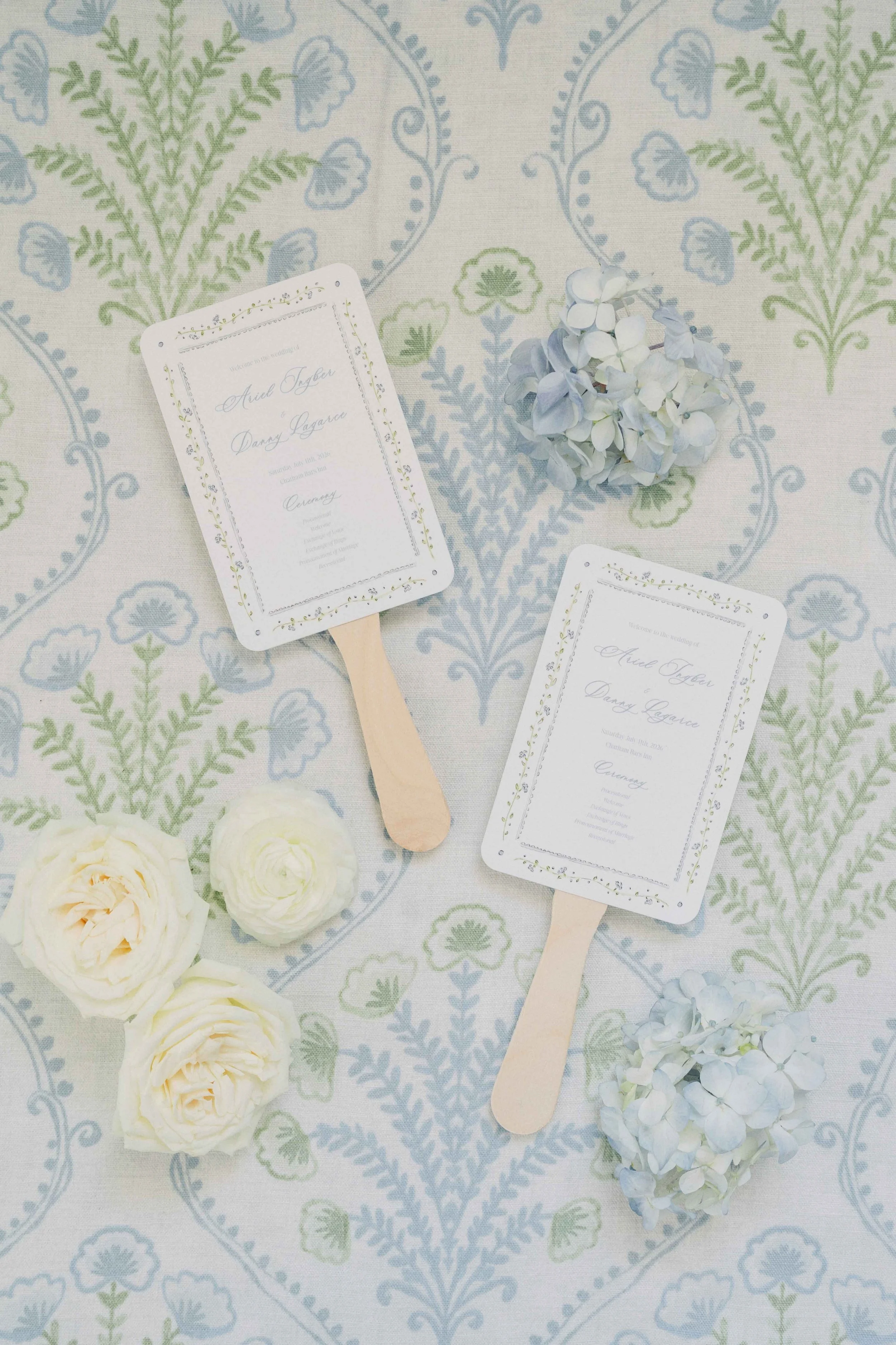 Blue and green background with florals and wedding program fans on top