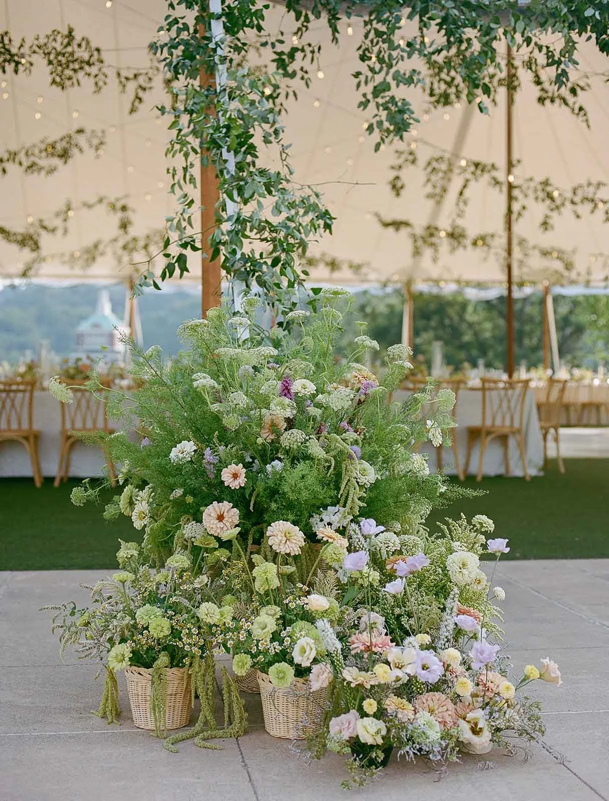 Whimsical wedding florals next to a luxury outdoor wedding reception tent featuring greenery and flowers