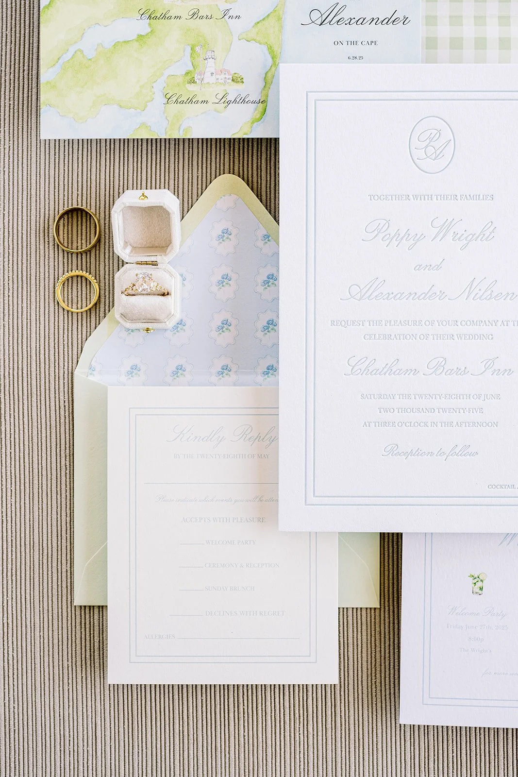 Custom blue and green wedding stationery with green envelopes, custom floral envelope liners, and elegant cards on a neutral background