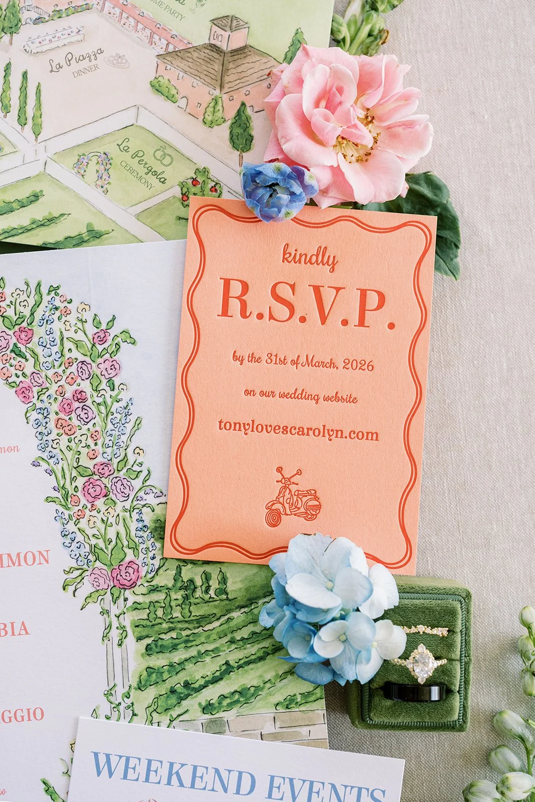 A wedding RSVP card for a destination wedding invitation suite with pink and blue flowers, wedding rings, and an illustrated watercolor map of a garden or estate.