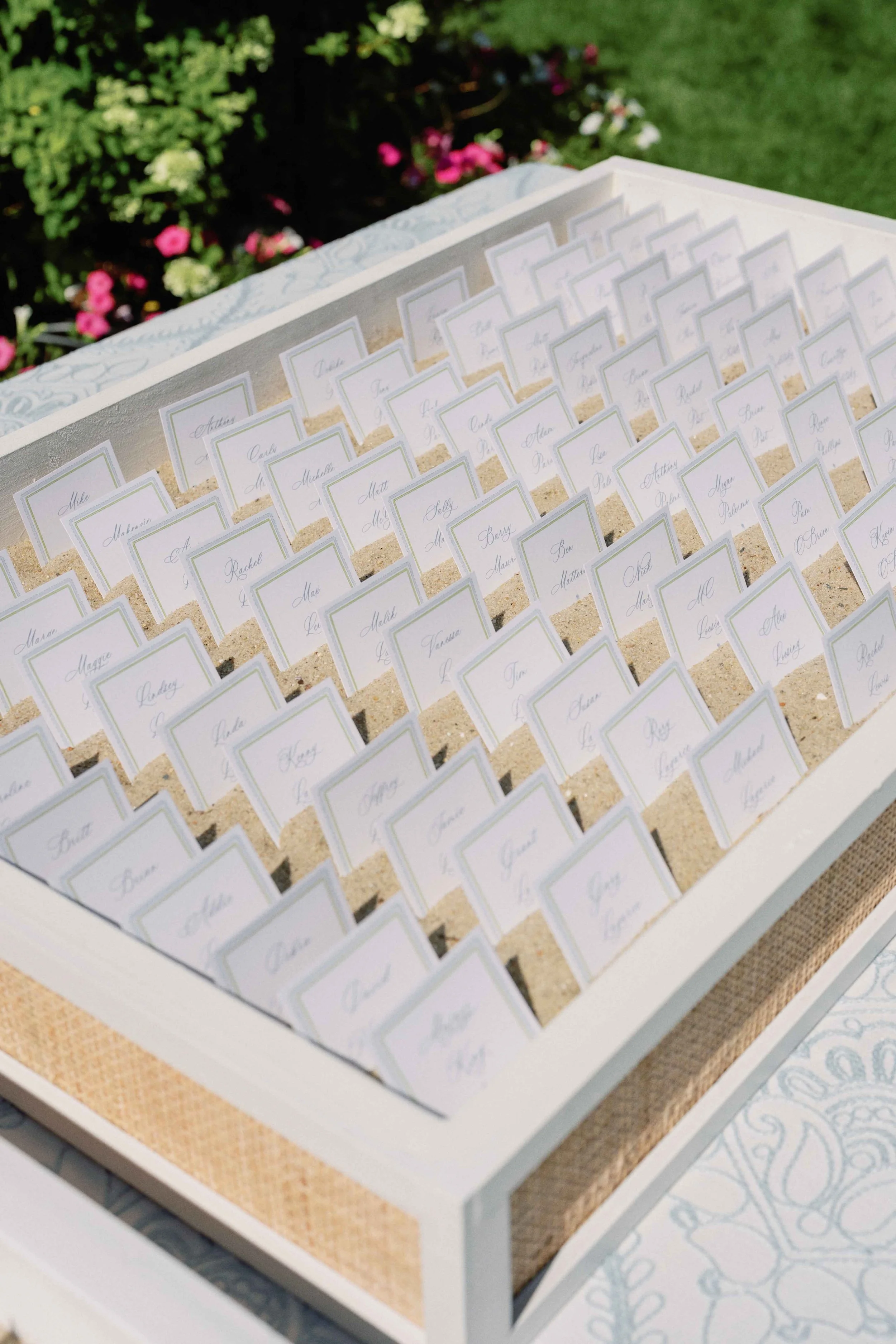 A baskets with sand holding name place cards for guests