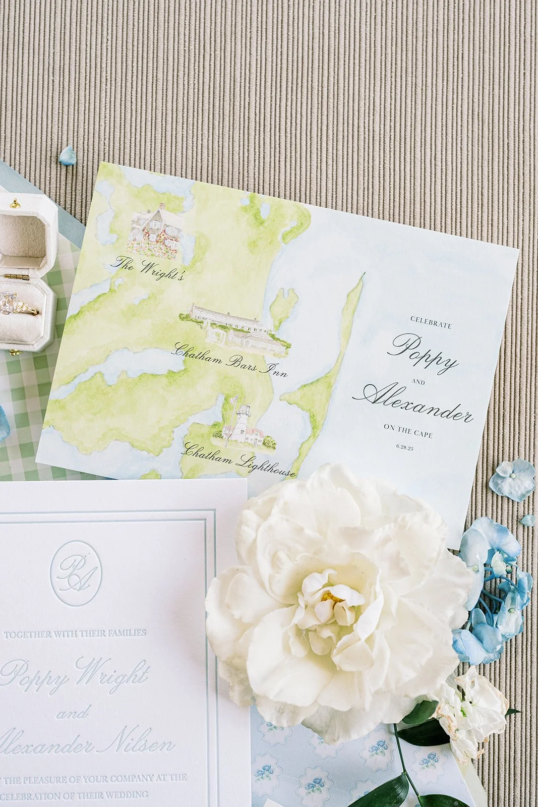 Custom wedding watercolor map next to a wedding invitation with real florals on a neutral background