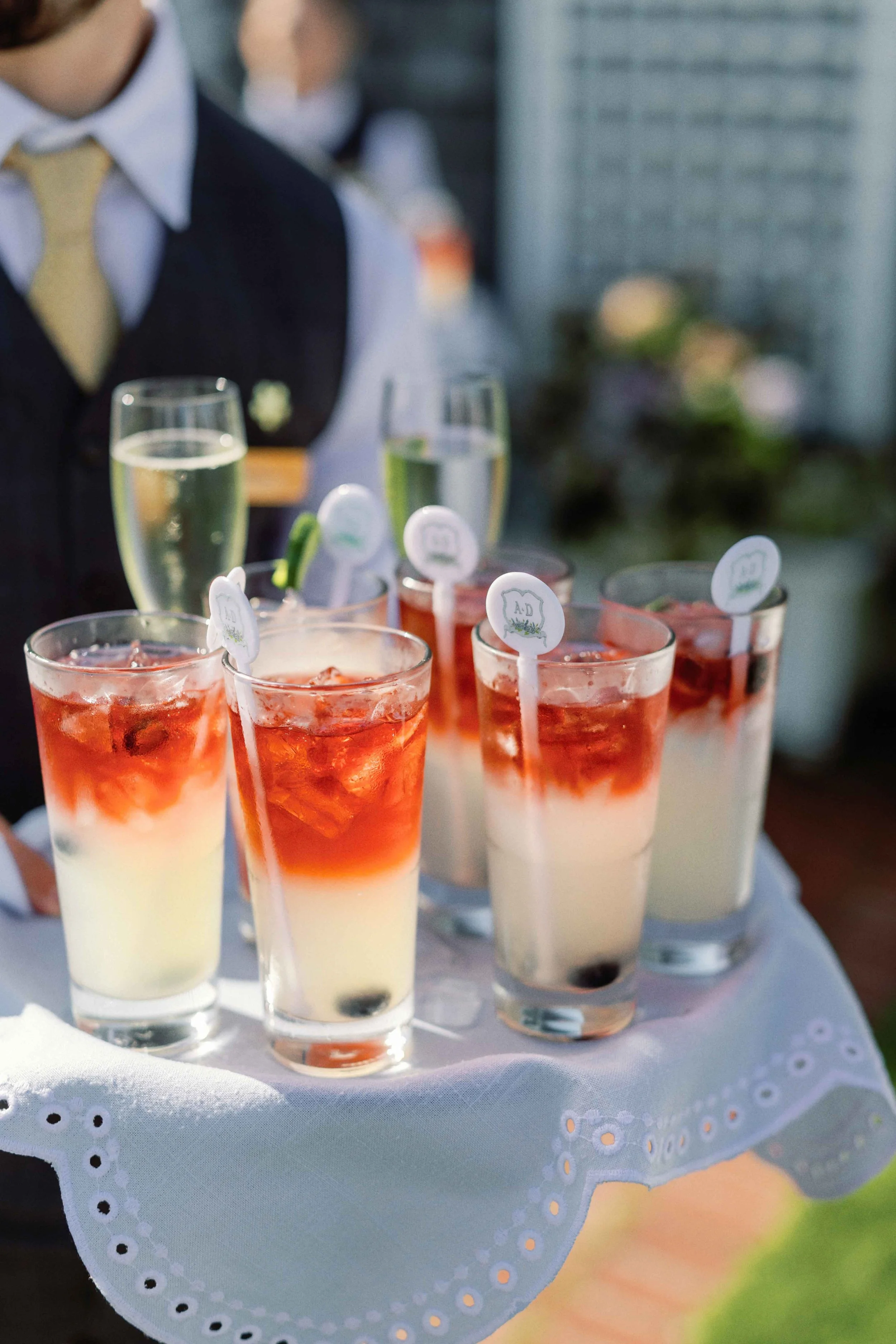 Person holding a plate of drinks that feature a custom stir stick with a wedding monogram