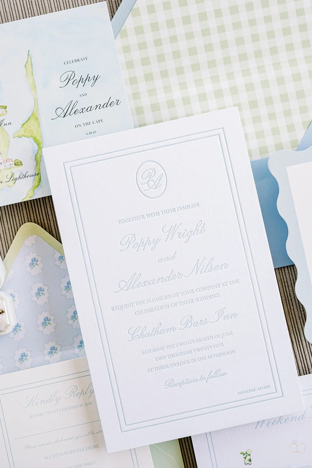 Custom, elegant coastal wedding invitation on top of other wedding stationery pieces