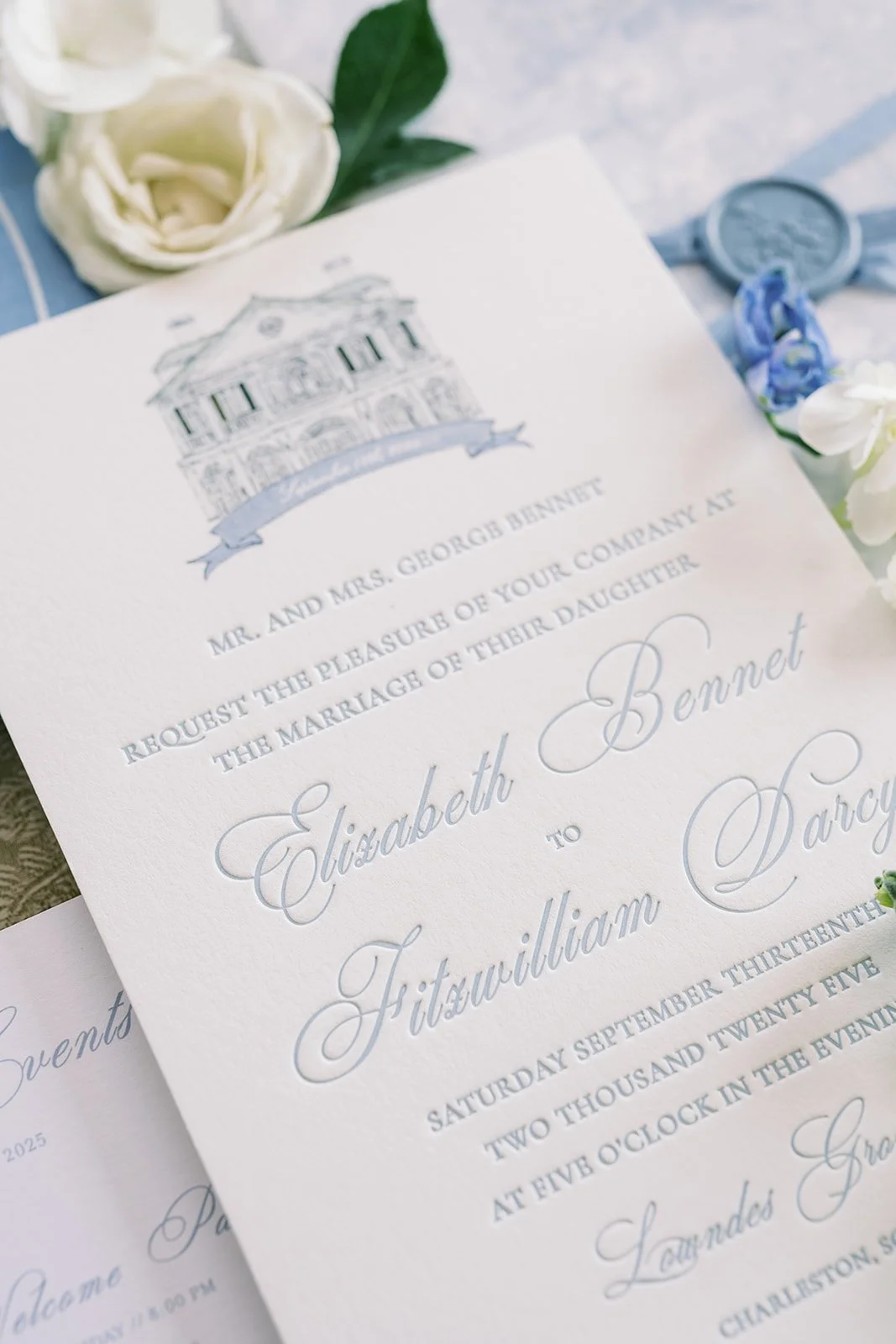Custom wedding invitation with a hand-drawn wedding illustration at the top of the card and elegant script writing surrounded by florals