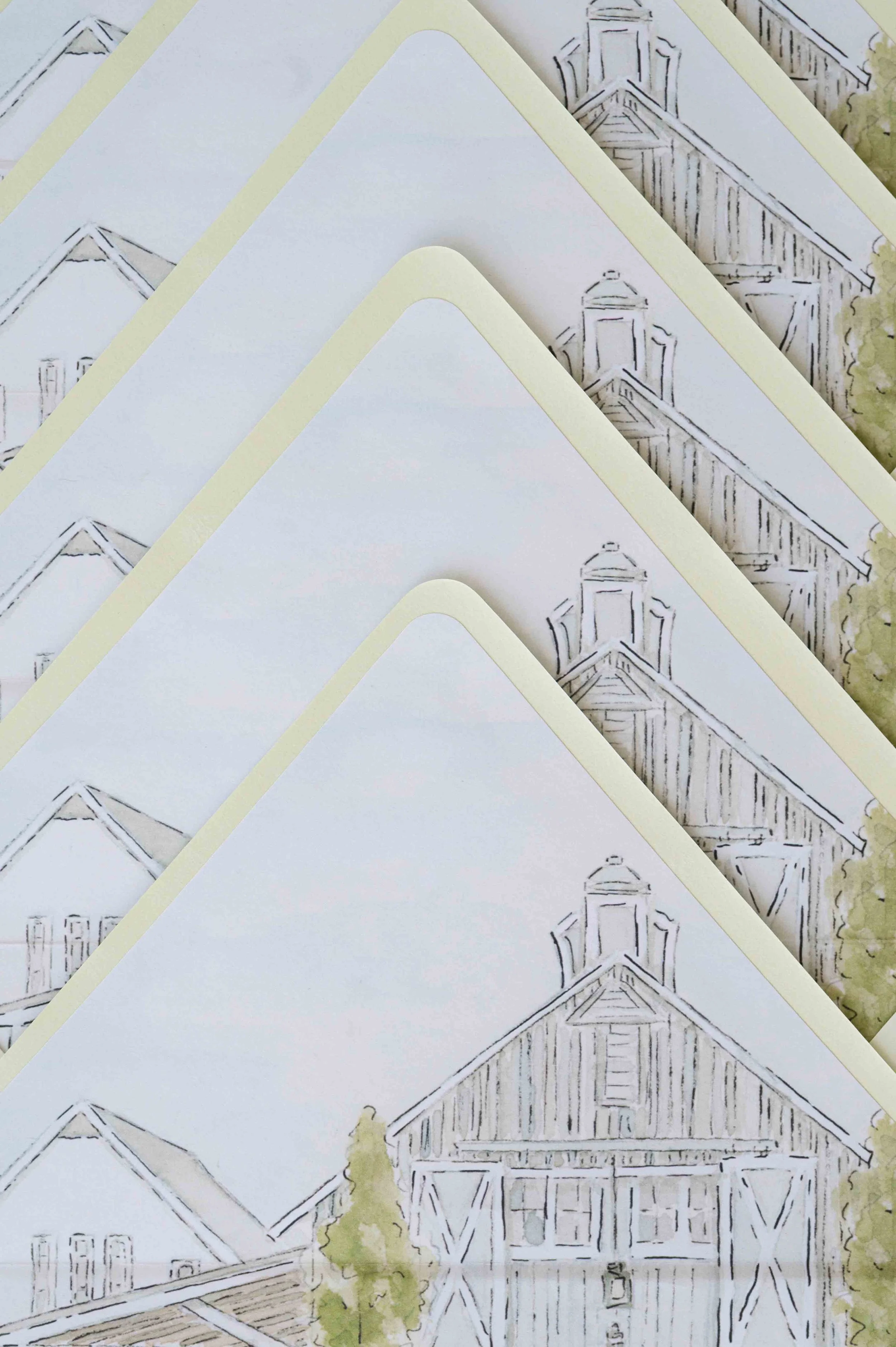 Stack of hand-painted envelope liners with a painting of a wedding venue in the background.