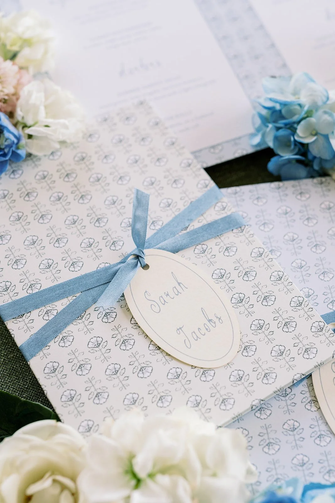 Nantucket-themed wedding stationery details featuring floral cards with a blue ribbon and name