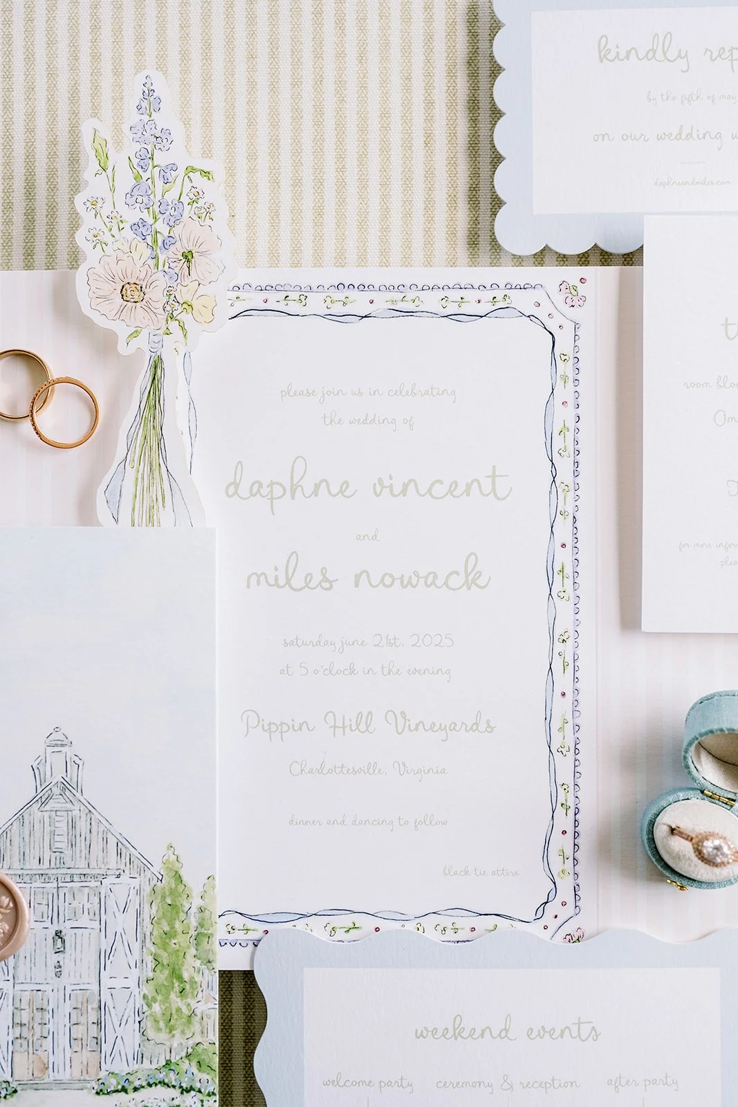 Wedding invitation with floral border, wedding details, and surrounding items including wedding rings and jewelry.