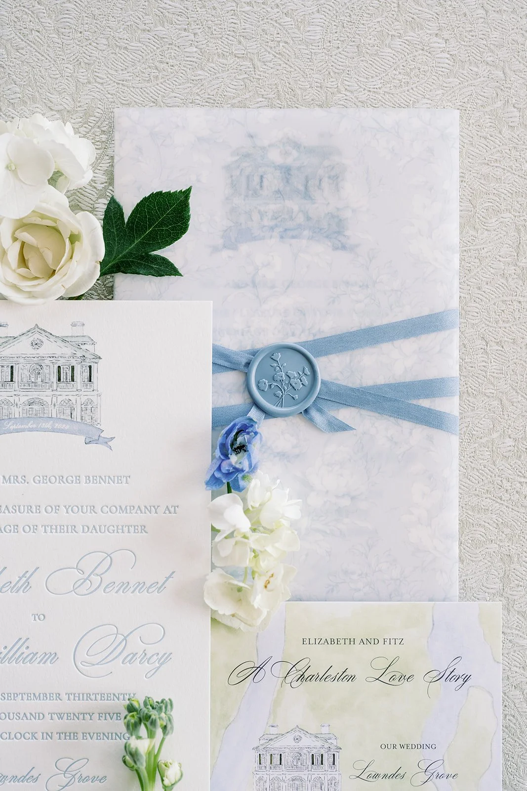 Wedding invitation with floral details, blue ribbons, and a blue wax seal