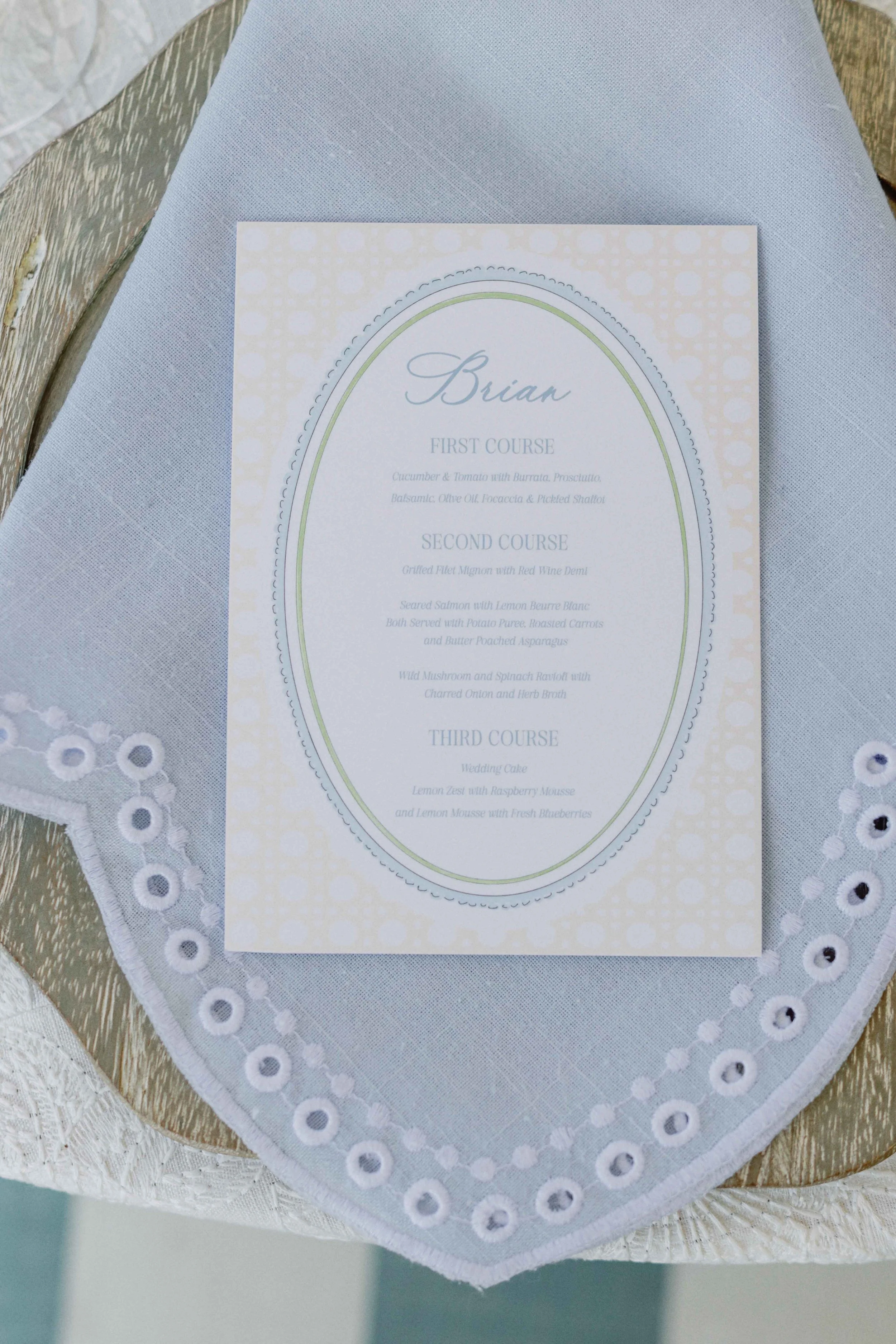 Custom wedding menu on top of a blue napkin on a table setting