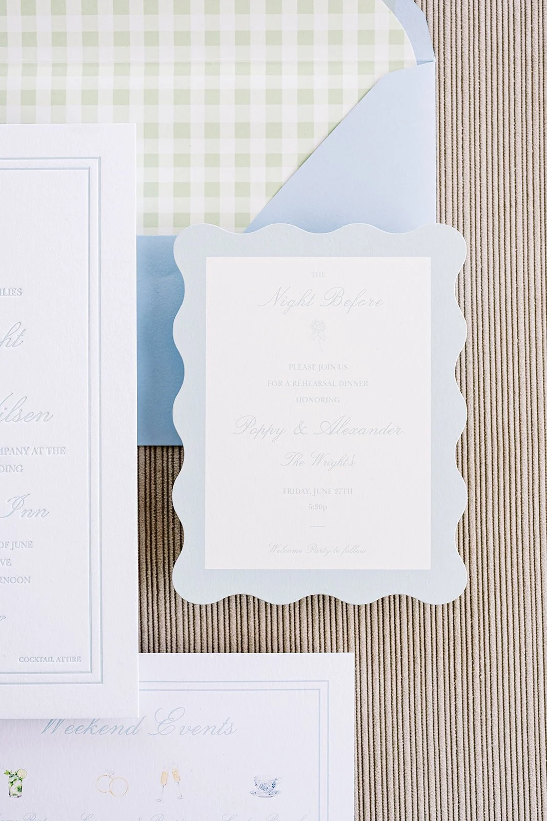 Scallop rehearsal dinner card next to coastal wedding stationery on a neutral background