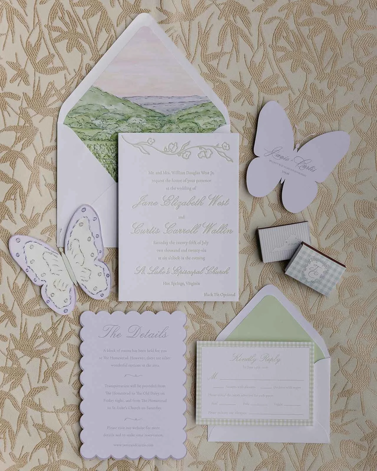 Flatlay of a whimsical wedding stationery suite featuring butterfly cut-outs, scallop detail cards, watercolor envelope liners, and more on a gold background