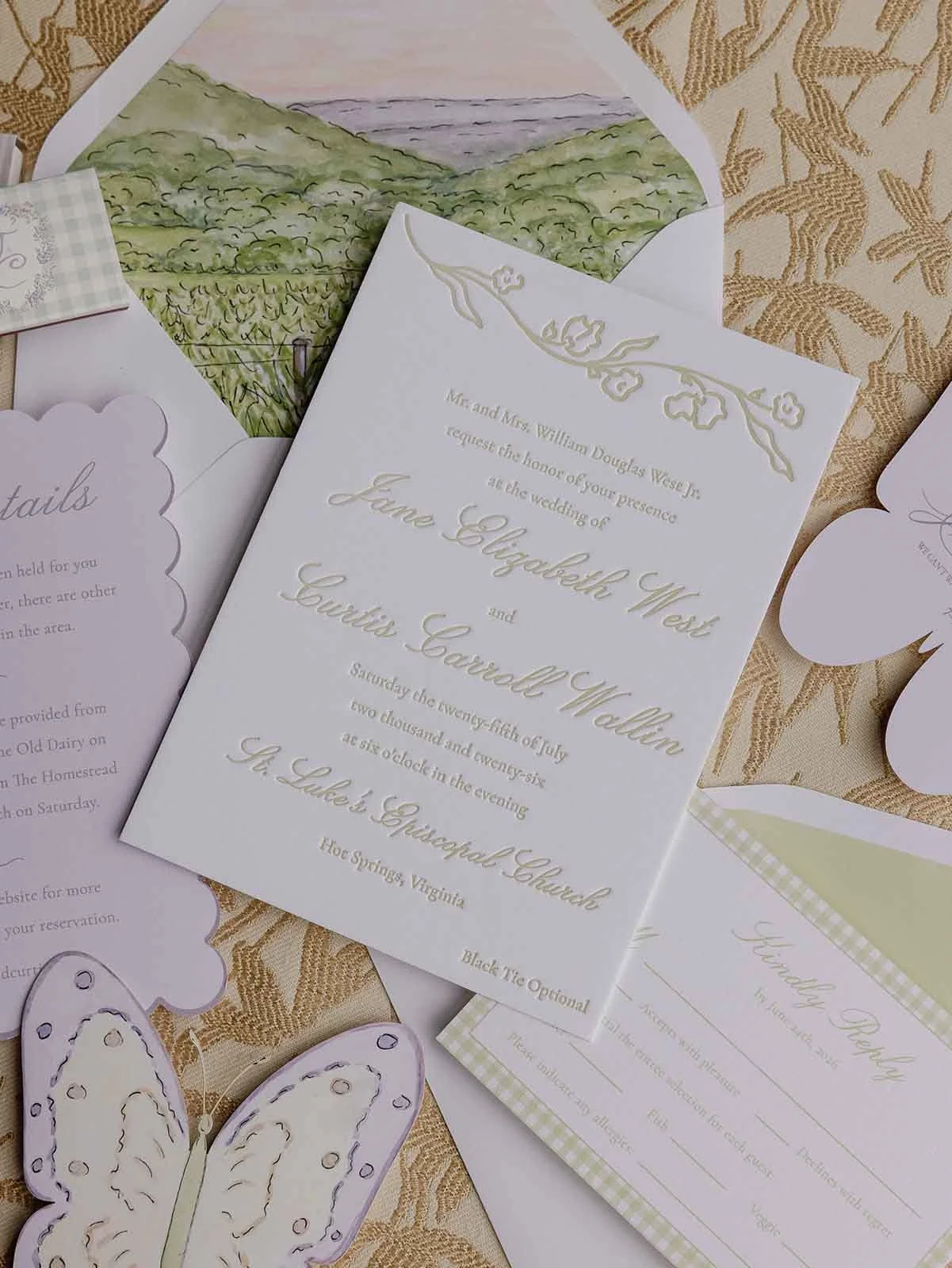 Close-up view of a wedding invitation featuring watercolor envelope liners, scallop cards, and butterfly cut-outs for a whimsical wedding stationery suite