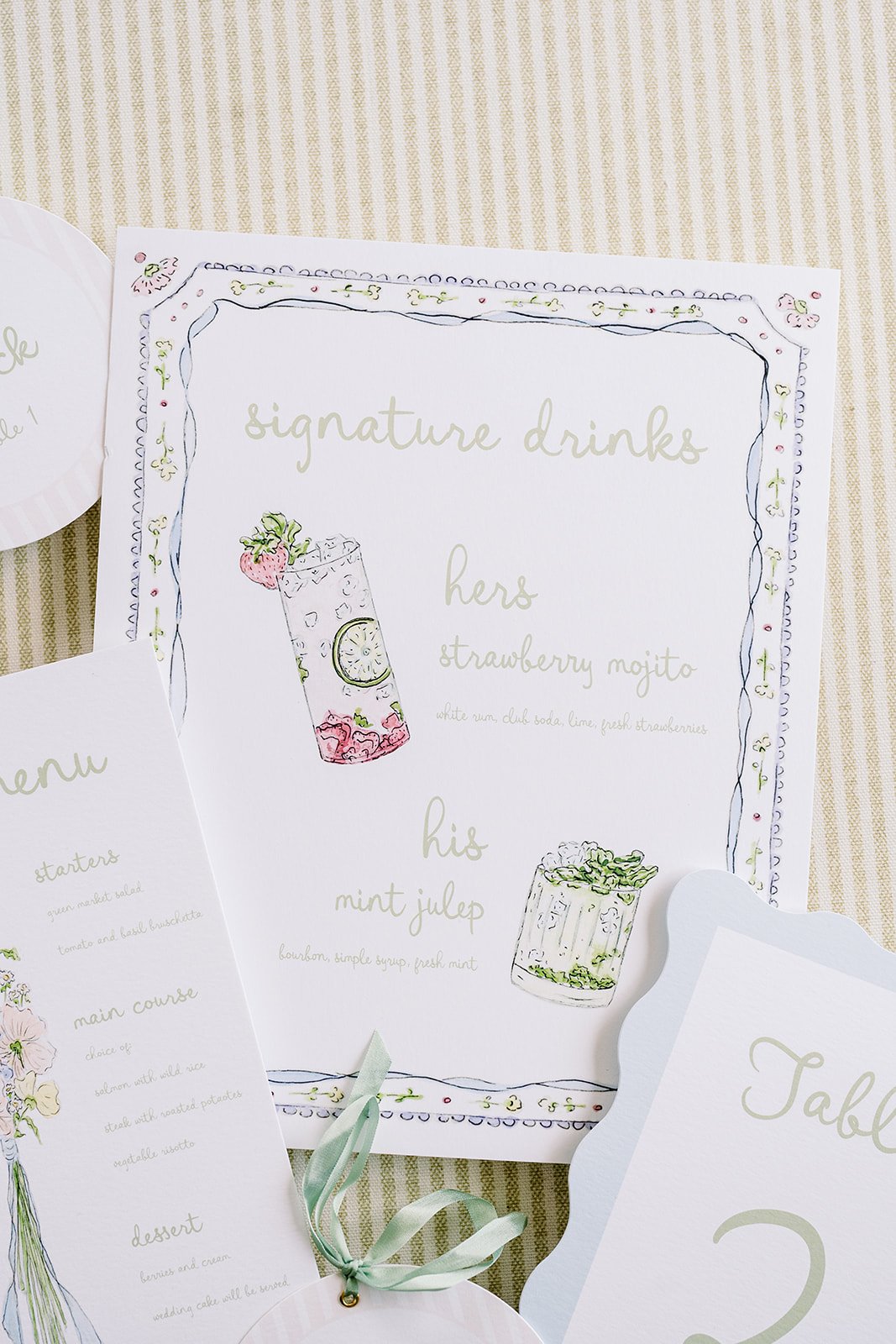 A menu card with floral border and handwritten-style text listing signature drinks and ingredients, including strawberry mojito and mint julep, alongside illustrations of the drinks.